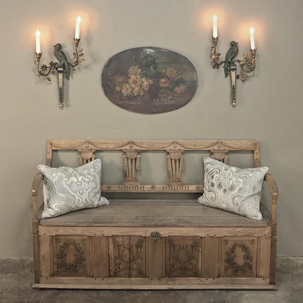 This pair of French Bagues style electrified wall sconces of carved and gilded wood features mirror image parrots flanked by two scrolled arms adorned with leaves supporting a candle cup, and date circa 1920. The firm of Maison Bagues is famous the