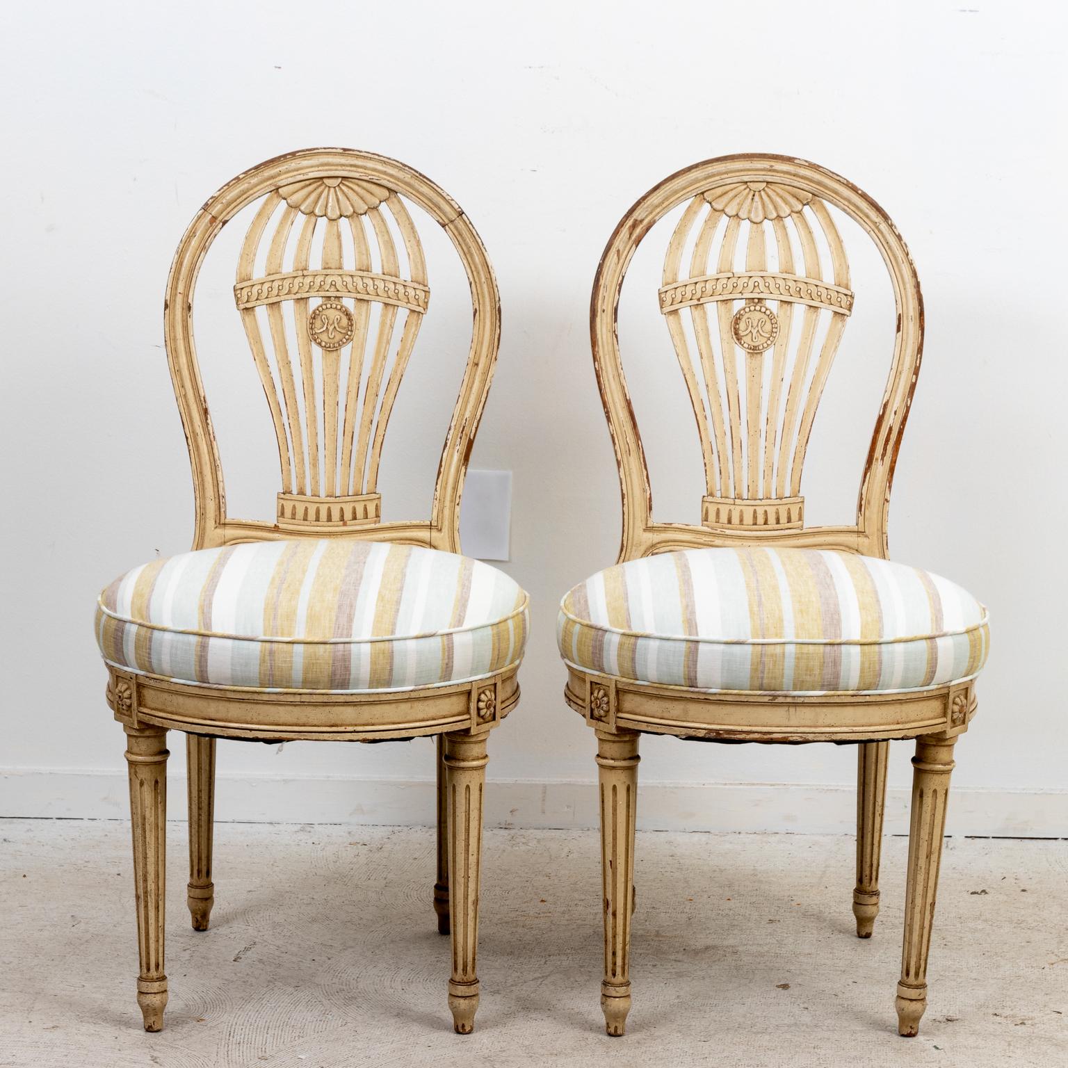 Pair of French pierced balloon back side chairs with newly reupholstered round seats in a soft striped linen fabric, circa 1920.