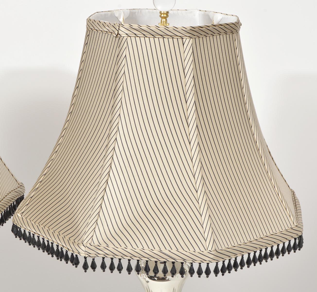 Mounted on patinated bronze bases the baluster shaped cut mercury glass gracefully reflect the light, early 20th century. Above the glass archantus shaped bronze mounts support the light fixtures. The elegant lampshades are trimmed with cut glass
