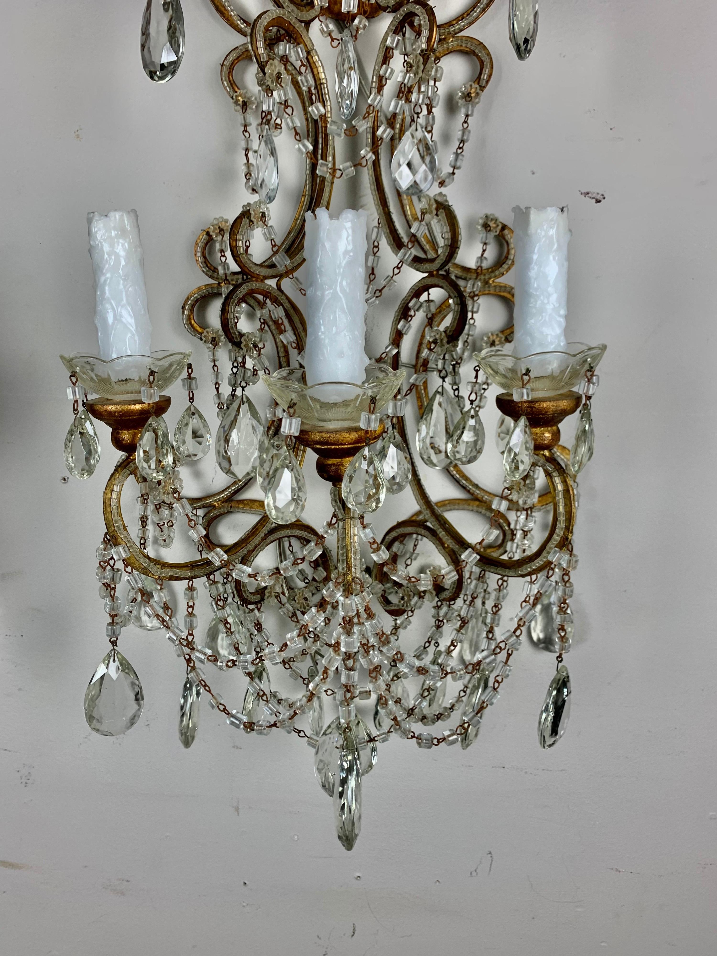 Pair of hand beaded 6-light Italian crystal sconces with macaroni shaped beaded garlands throughout. The gilt metal frames are finished in a gold coloration. The sconces are from the 1940's and have been newly rewired with drip wax candle covers.