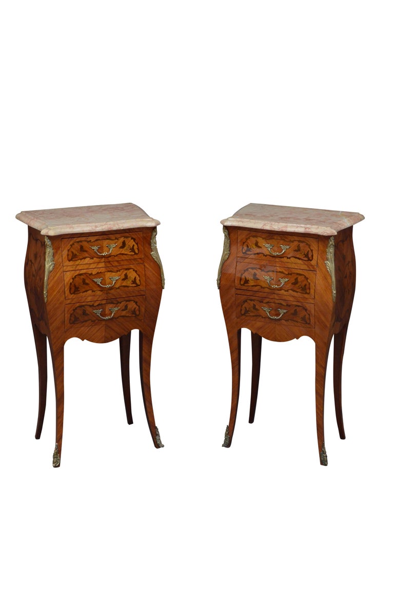 K0530 Pair of attractive kingwood bombe bedside cabinets, each with original serpentine marble top and three inlaid drawers fitted with original handles and flanked by ormolu decoration.
This pair of antique bedside cabinets is in home ready