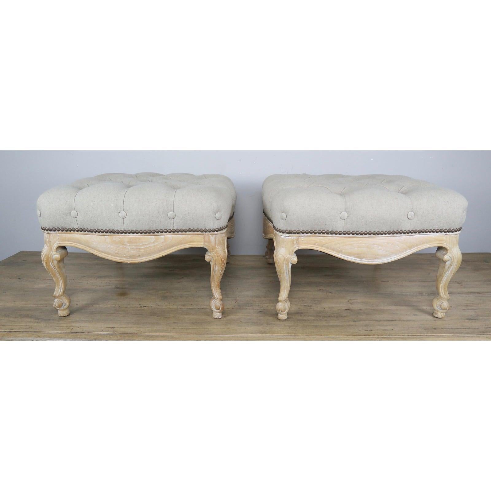 Pair of French Louis XV style natural wood benches newly upholstered in a neutral tufted Belgium linen textile and finished with antique colored brass nailhead trim.