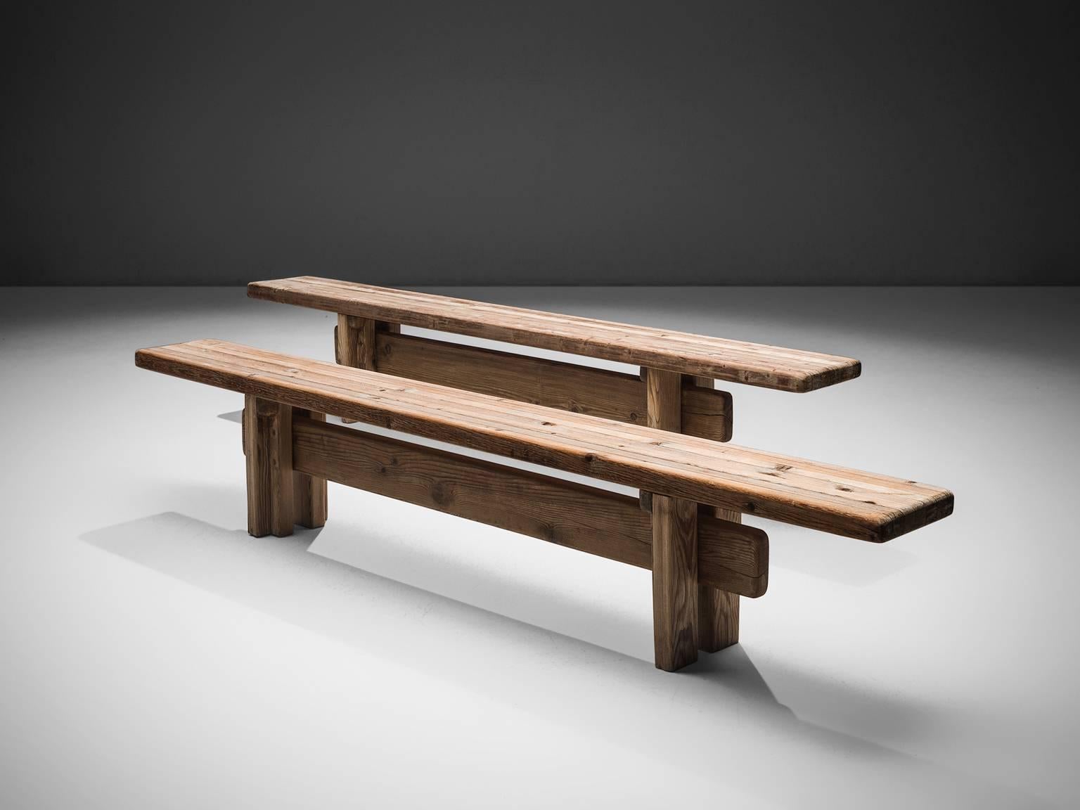 Set of two pine benches, France, circa 1950. 

These pine wooden benches are robust and architectural in their design. The bulky benches are made of beautiful pine wood which developed a nice, rustic patina from age and use. The traditional wooden