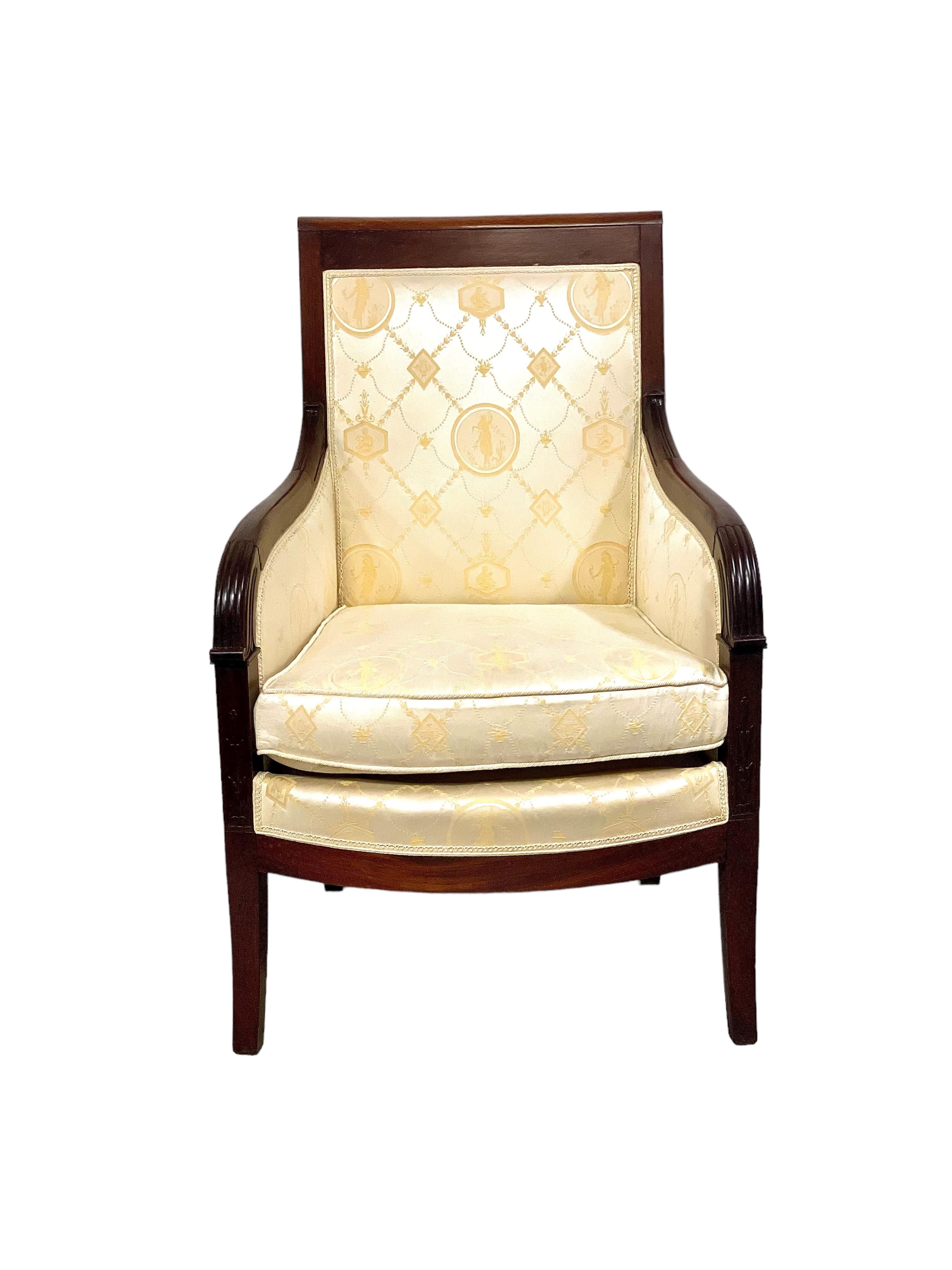 A handsome pair of fabric Bergère armchairs in solid mahogany and mahogany veneer. Dating from the Empire period, these very striking chairs are in excellent condition, with exquisitely woven cream fabric upholstery featuring a classic design of