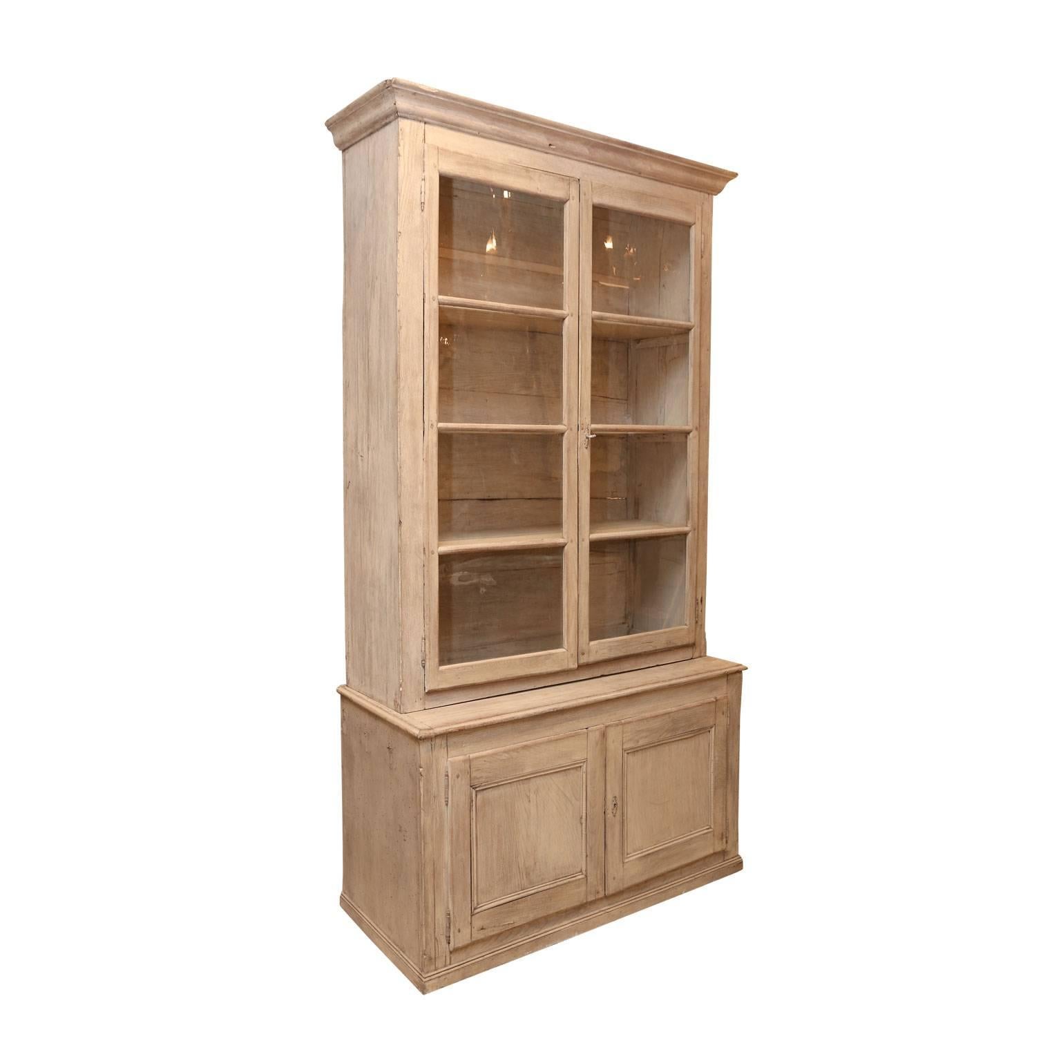 Pair of French bibliotheques: massive late 19th century bookcase altered to create a matching pair of bibliotheques. Bibliotheques each feature two glass panelled upper doors and two-door lower cabinet storage with shelf. All doors are mortise and