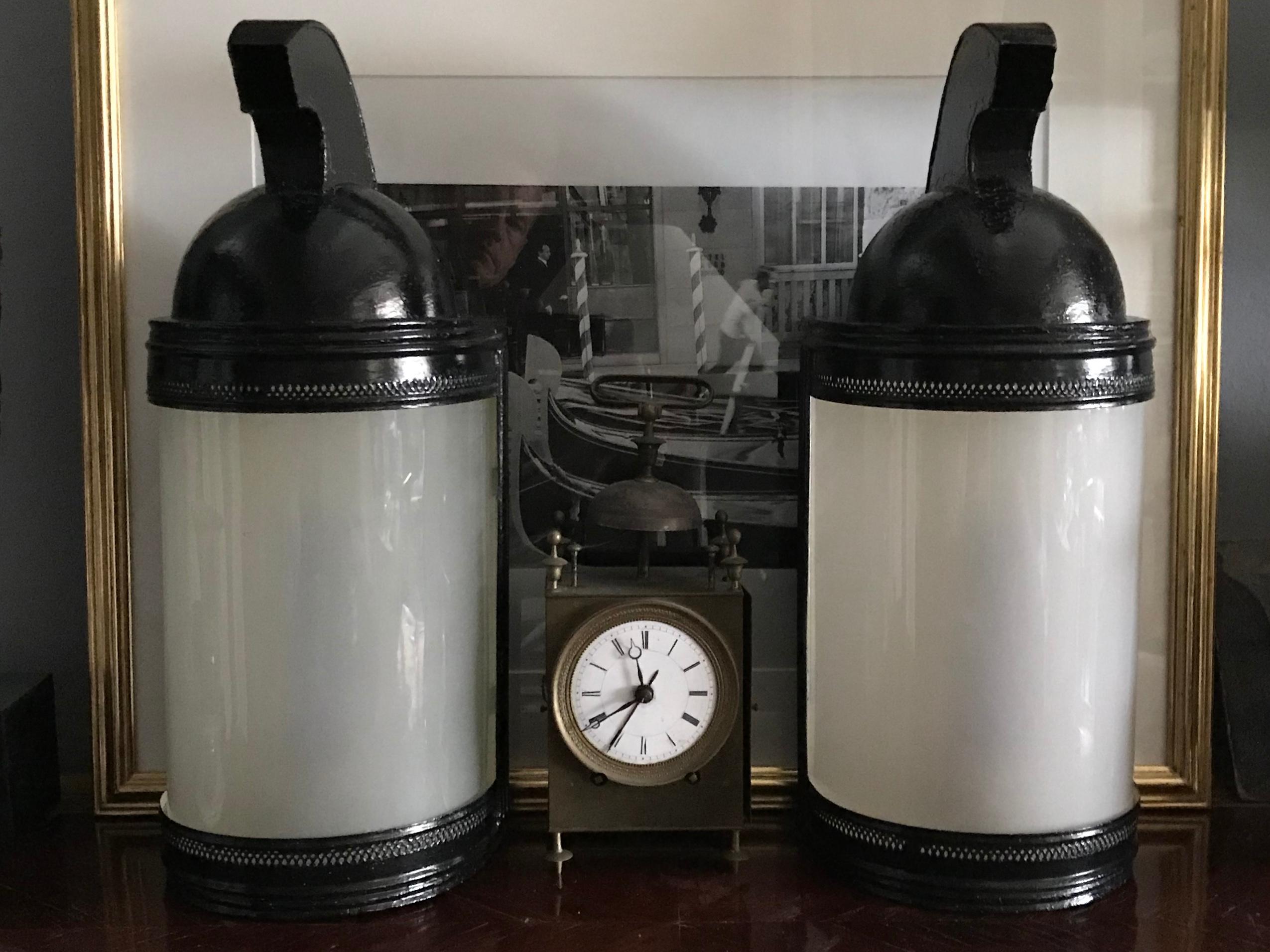 Pair French black tole Spartan helmet table lamps. Pair of black painted tole table lamps in the form of Spartan / Roman helmets with curved opaque glass and white interiors. Newly electrified in black silk cord with switch. Perfect for console