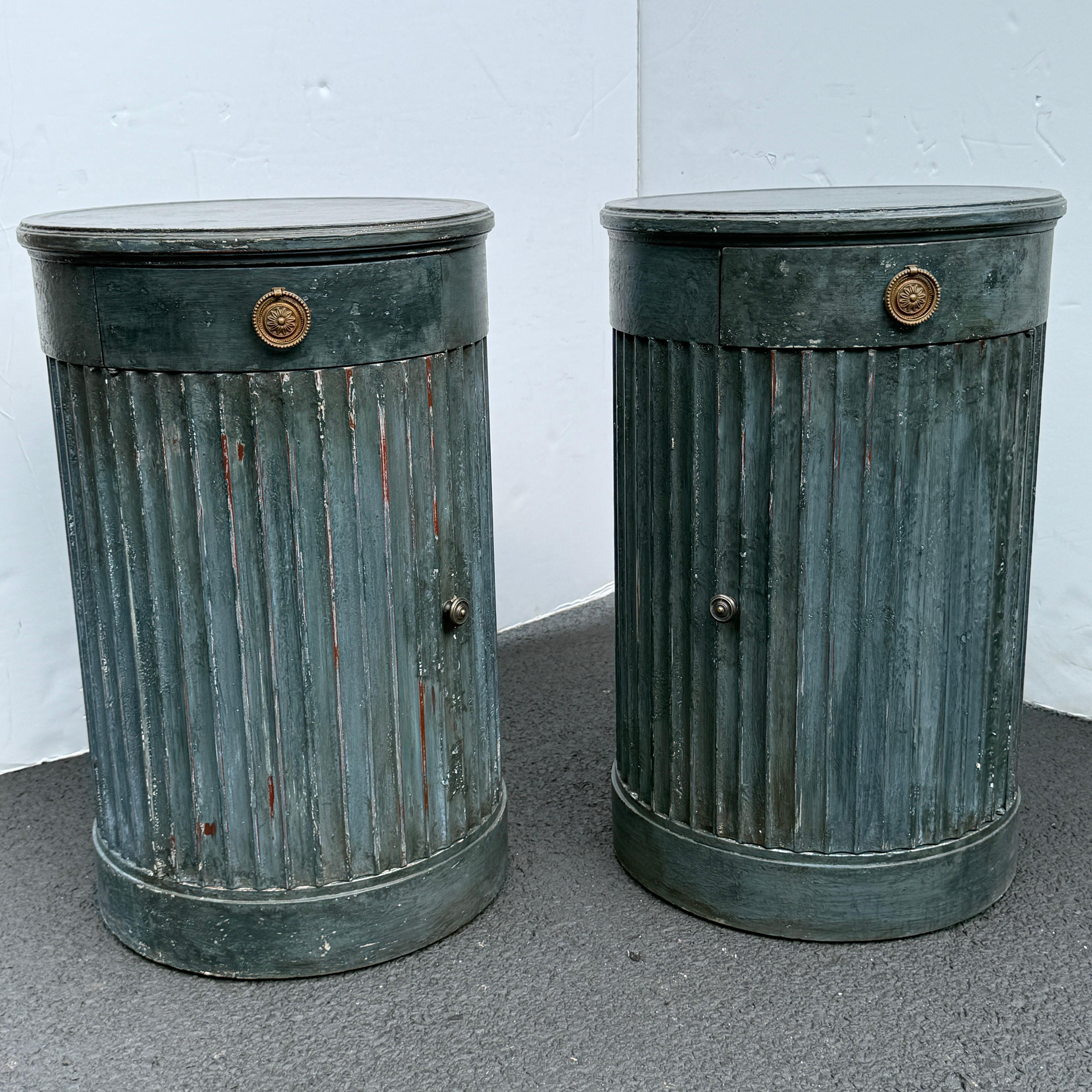 This pair of side tables with a single drawer and cabinet below have been constructed from solid wood. The interior features a shelf for additional storage. Classic details on this set include a hand-applied finish with bronze hardware. This set