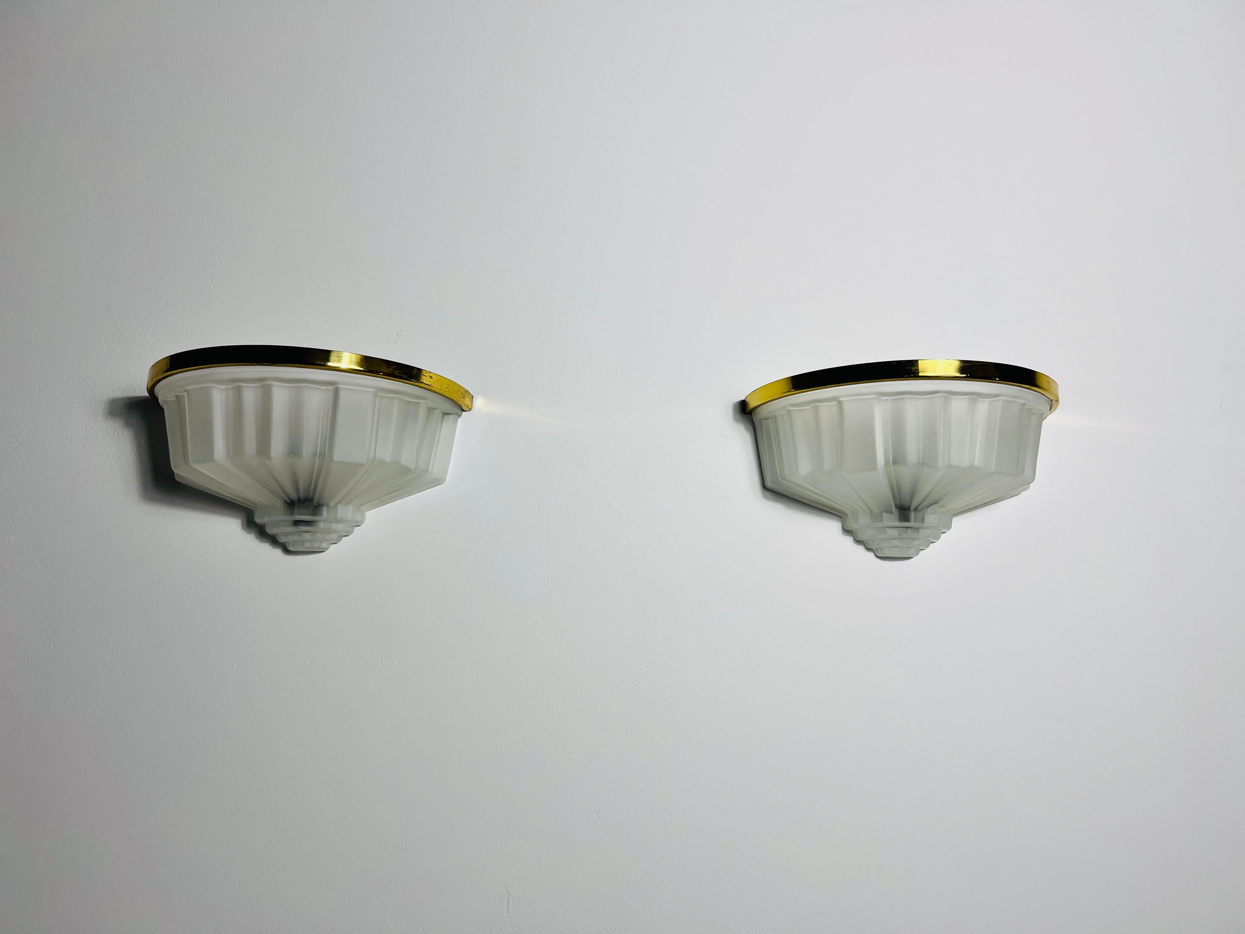 Una bellissima coppia di lampade da parete in stile Art&Deco realizzate in Francia negli anni '40. Queste lampade sono caratterizzate da un design elegante e senza tempo, che mette in mostra lo stile distintivo dell'epoca Art Deco. Realizzati in una