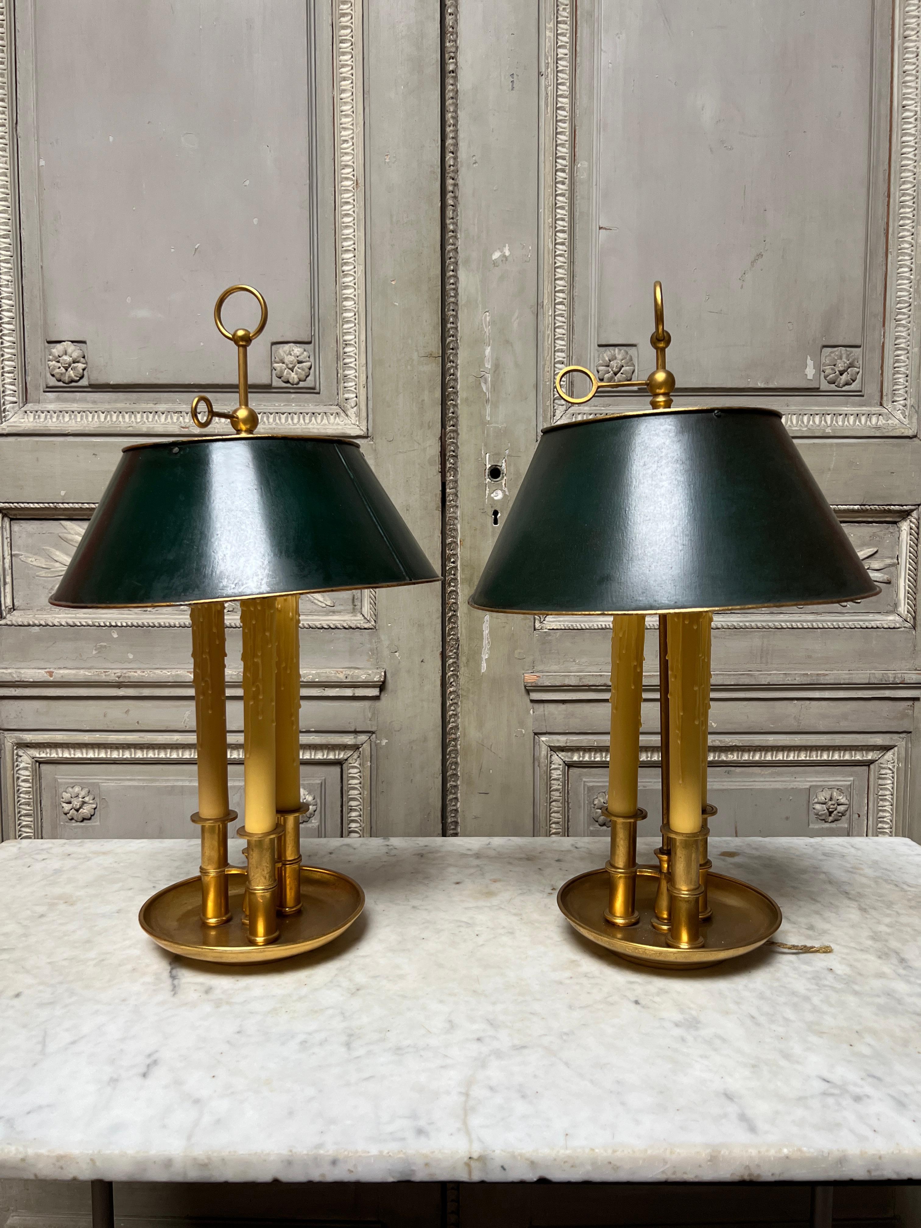 A pair of French Louis XVI style brass bouillotte lamps with green painted tole adjustable shades.  
These very functional and decorative lamps are in need of new wiring which can be done locally for an additional fee.  
