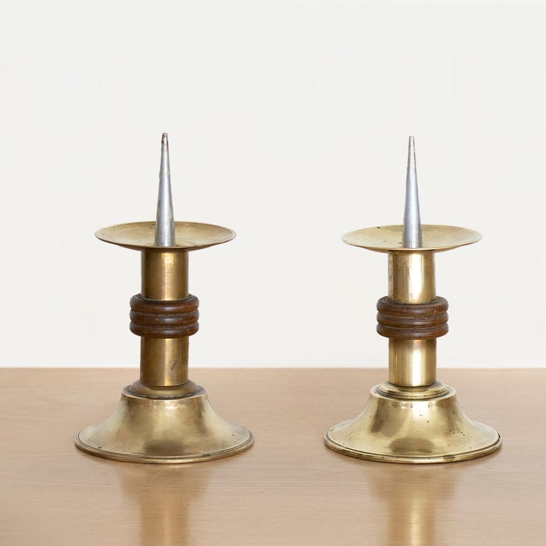Pair of vintage 1930's Art Deco brass candle holders from France. Nice age and patina on brass and center wood ribbed ring detail. Circular stand with spike to hold pillar candle. Sold as a pair of two. 