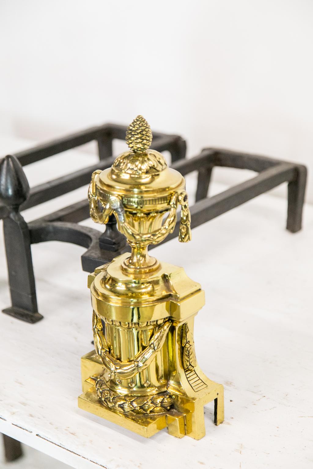 These andirons have neoclassical urns with floral swags on a straight plinth base. There are double steel supports with acorn finials. Each is signed: 