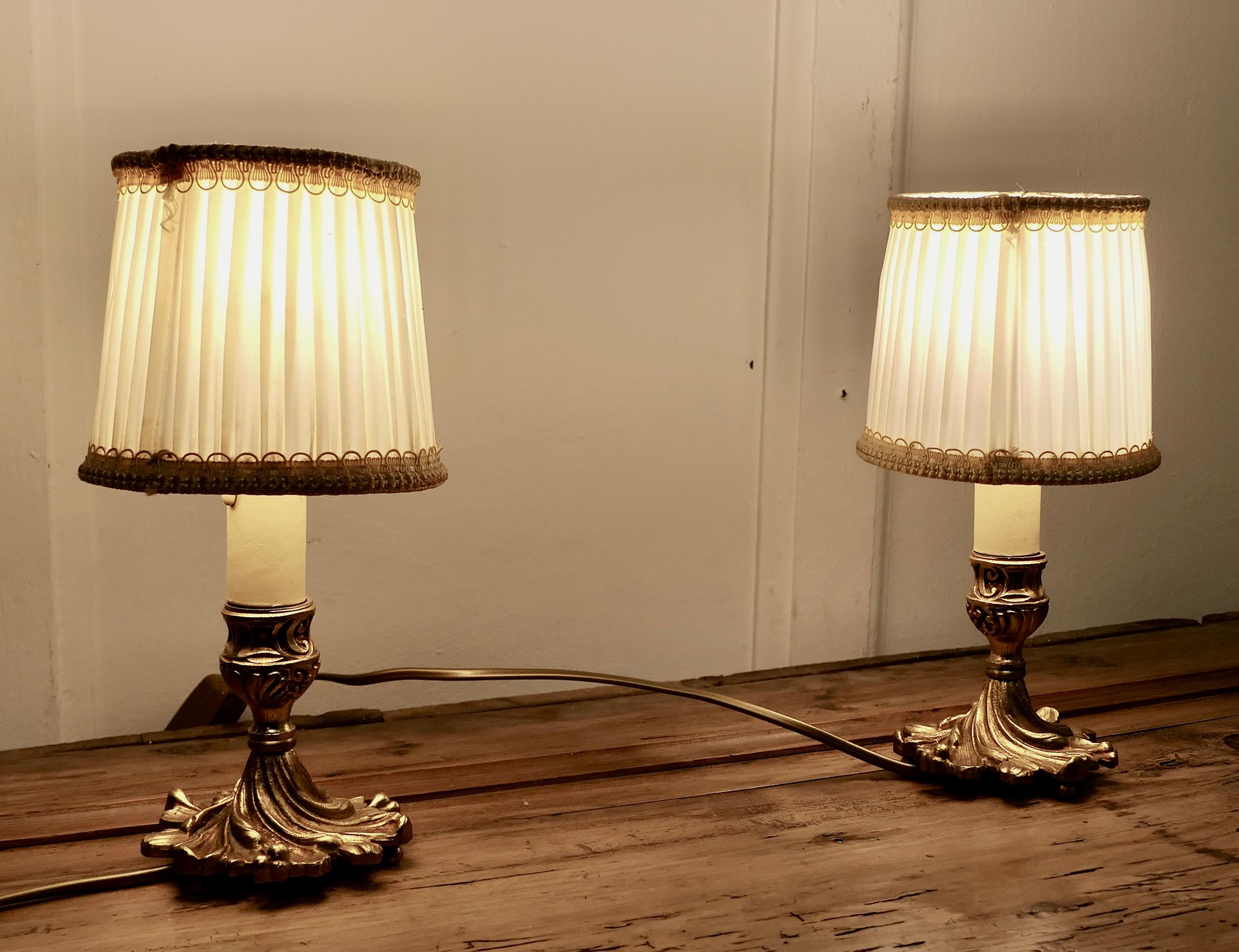 Pair of French Brass Bedside Lamps   

These are a good quality pair of small decorative bedside lamps, the bases are made in solid brass in the shape of acanthus leaves
They have original cream shades 
The lamps are good quality and in good working