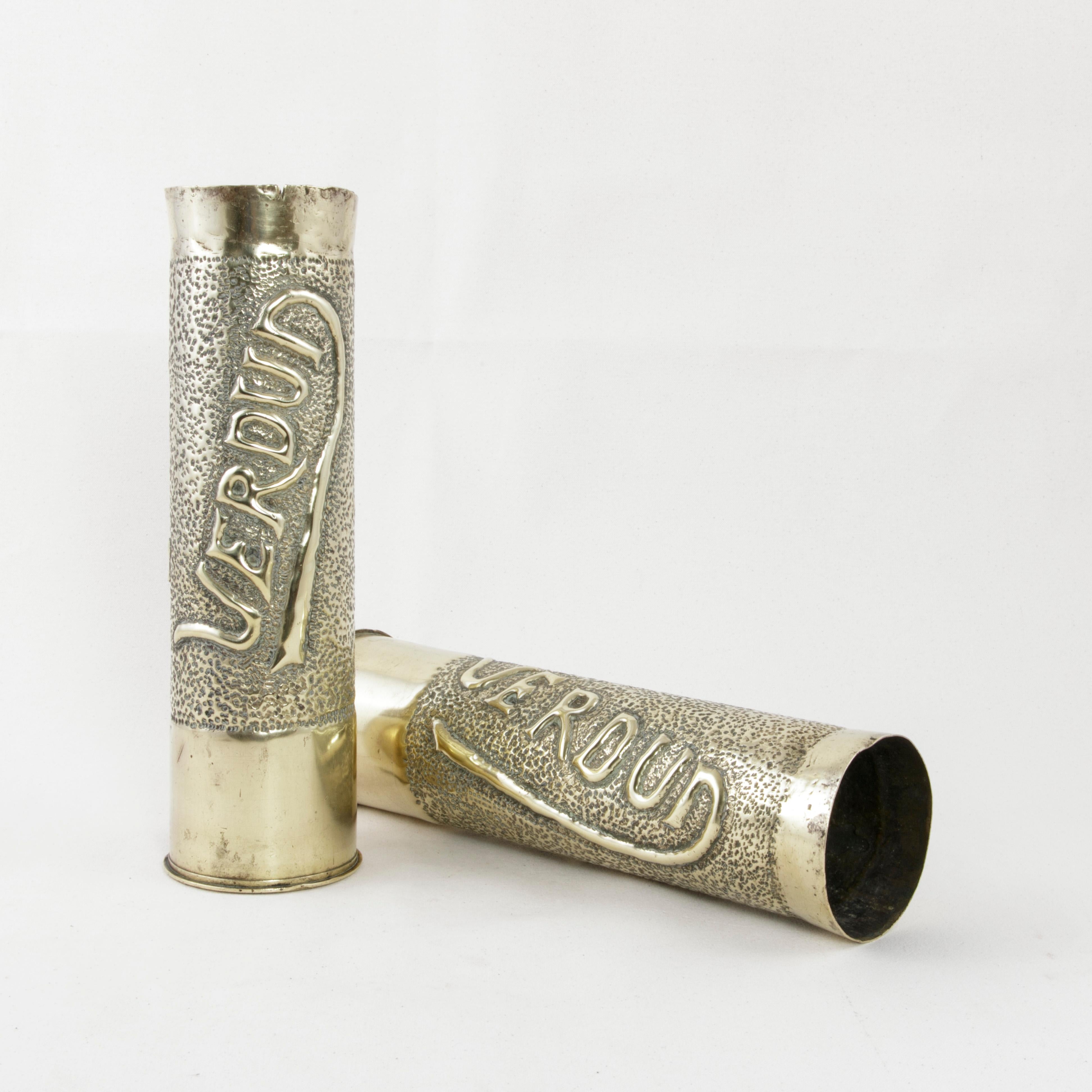 Made from spent artillery shells during the first World War, this pair of brass trench art vases features a repousse oak leaf on one side, and the name Verdun in Art Nouveau style lettering on the other. Verdun, fought in 1916, was one of the