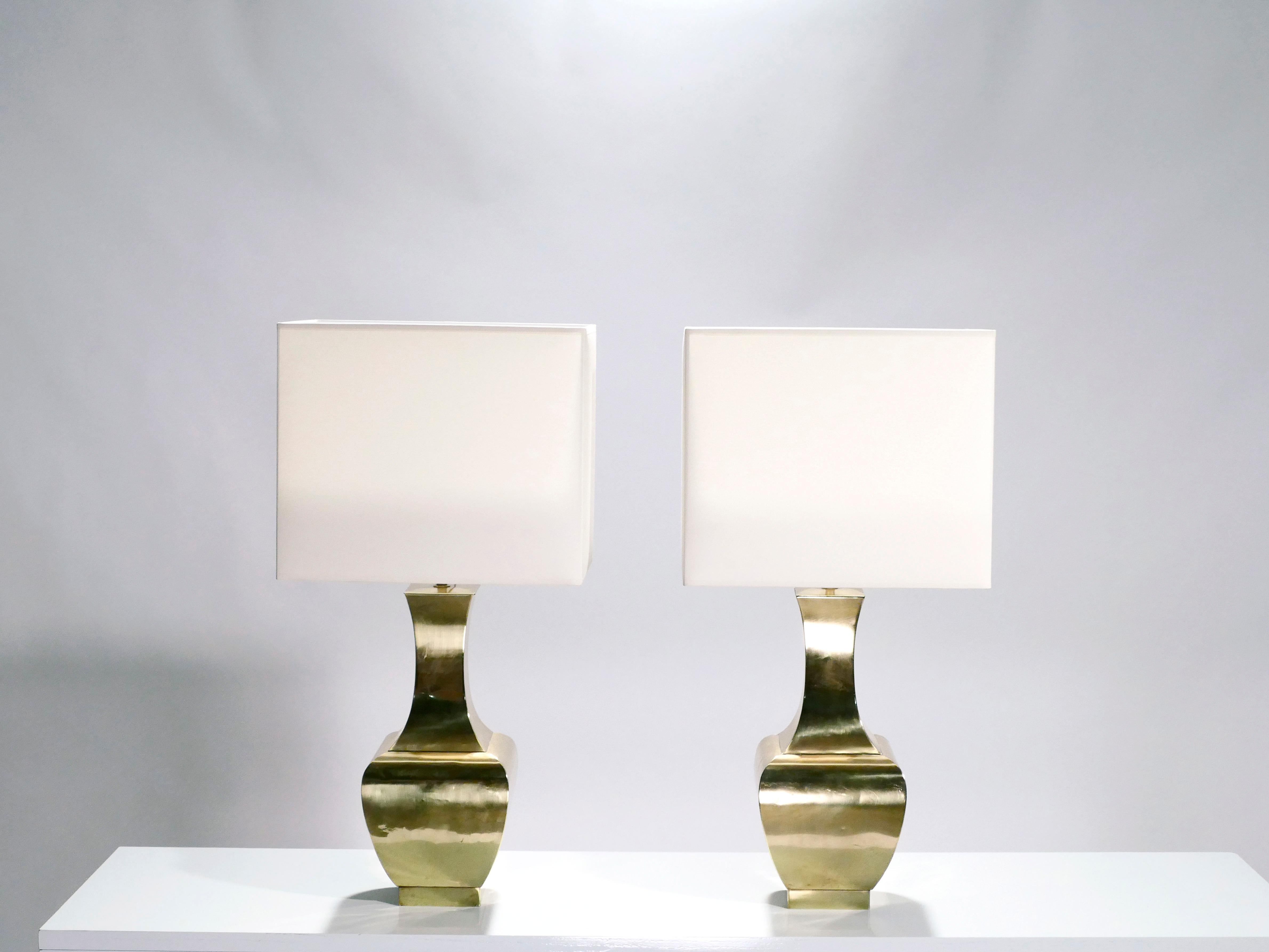 There’s a classic beauty to this French 1970s pair of lamps. Their brass structure has the fluid, dramatic curves of thrown pottery, matched with the bright shine of the metal. Offsetting the feminine shape of the base, a solid square lampshade