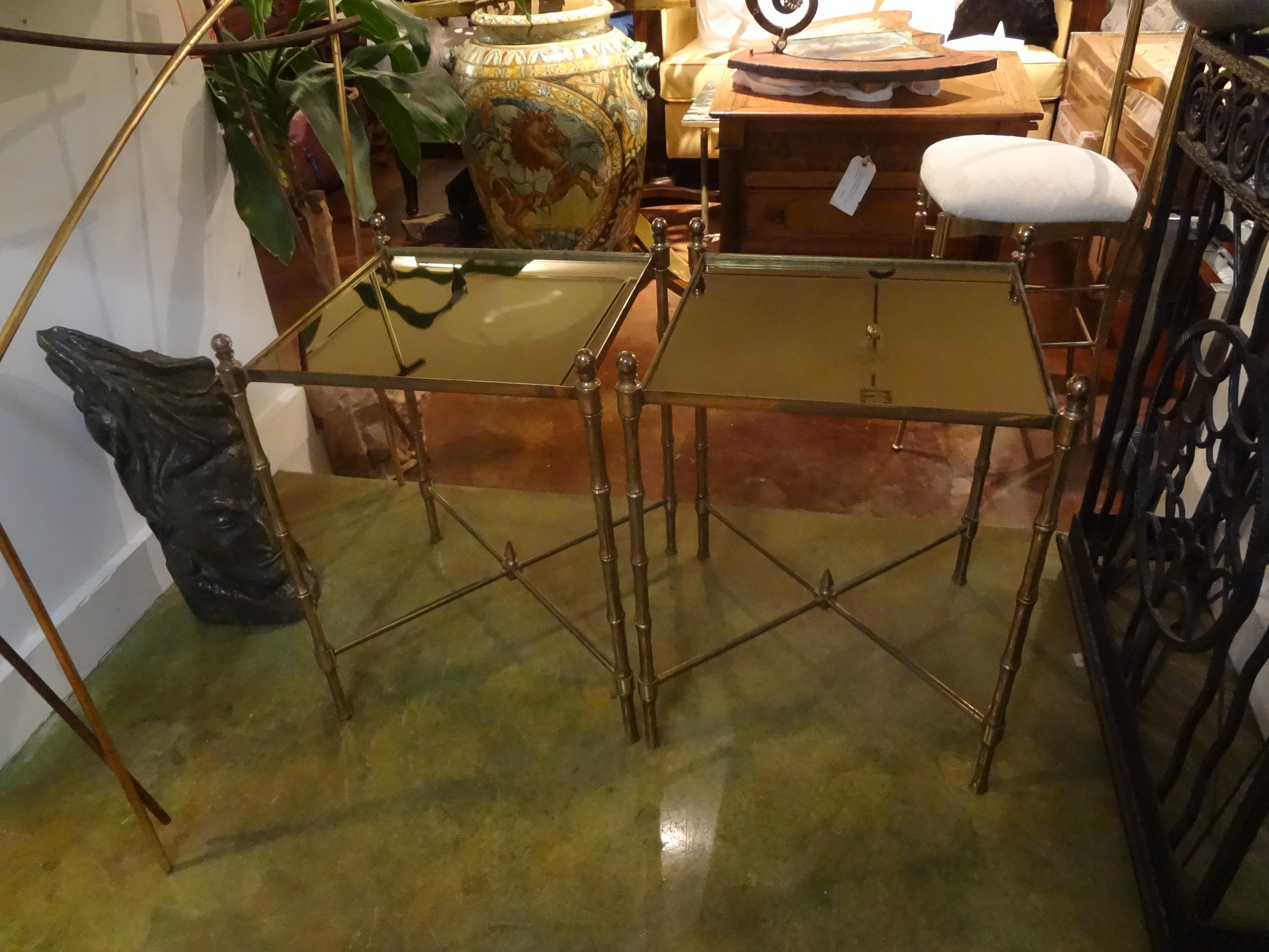 Lovely pair of French faux bamboo brass tables with bronze mirrored tops. This great pair of tables or gueridon are in the style of Maison Jansen or Maison Baguès and date to the 1940s. These Hollywood Regency brass tables are perfect as side