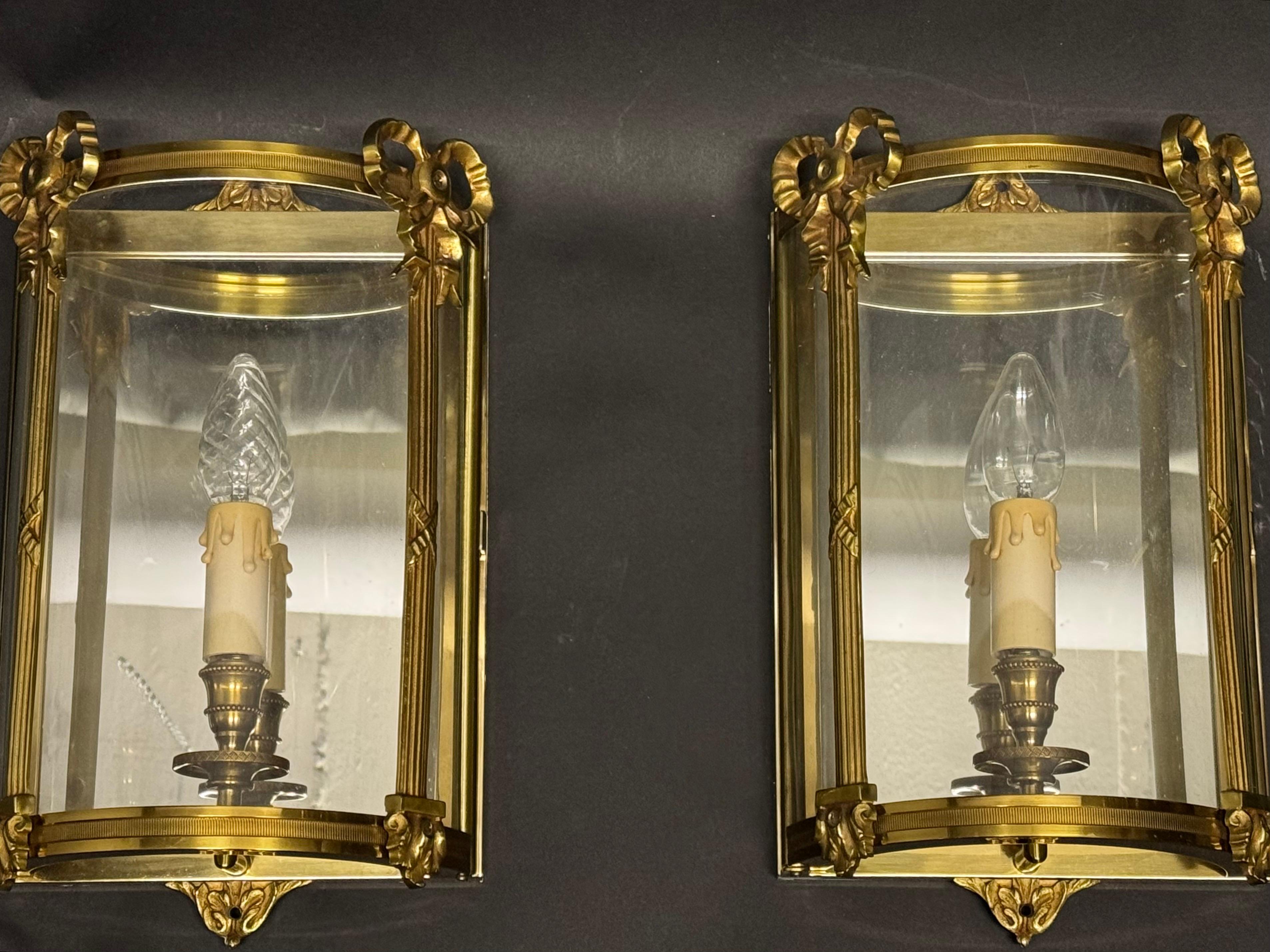 Un par de apliques de media linterna con espejo,  Francia, hacia la década de 1970.
Estos apliques de la más alta calidad están fabricados en bronce macizo, rodeados por tres paneles de cristal y una placa trasera rectangular de espejo.
Casquillo: