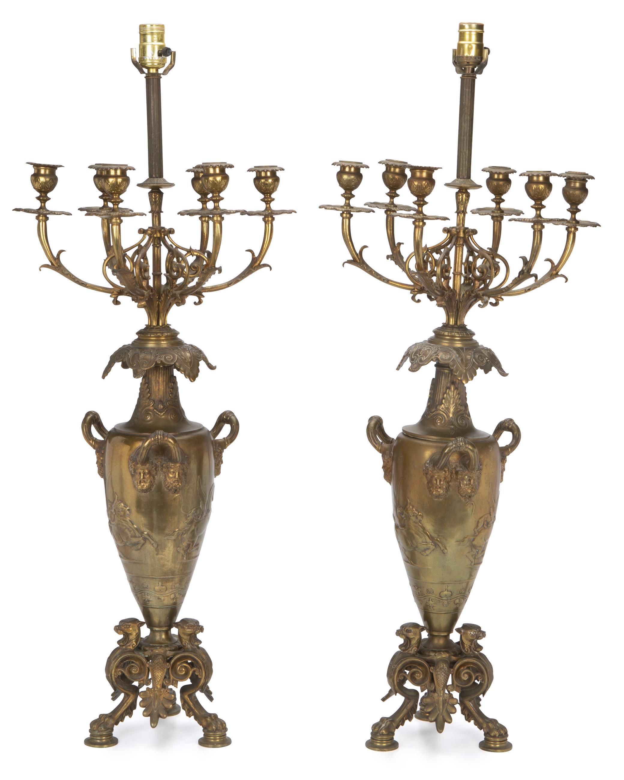 Intricate pair of French bronze six-light candelabra mounted to lamps.
Early 20th century.
Each lamp depicting an ovoid shaped body depicting a relief of a bull and dragon and decorated with six philosopher masks with three handles, issuing six