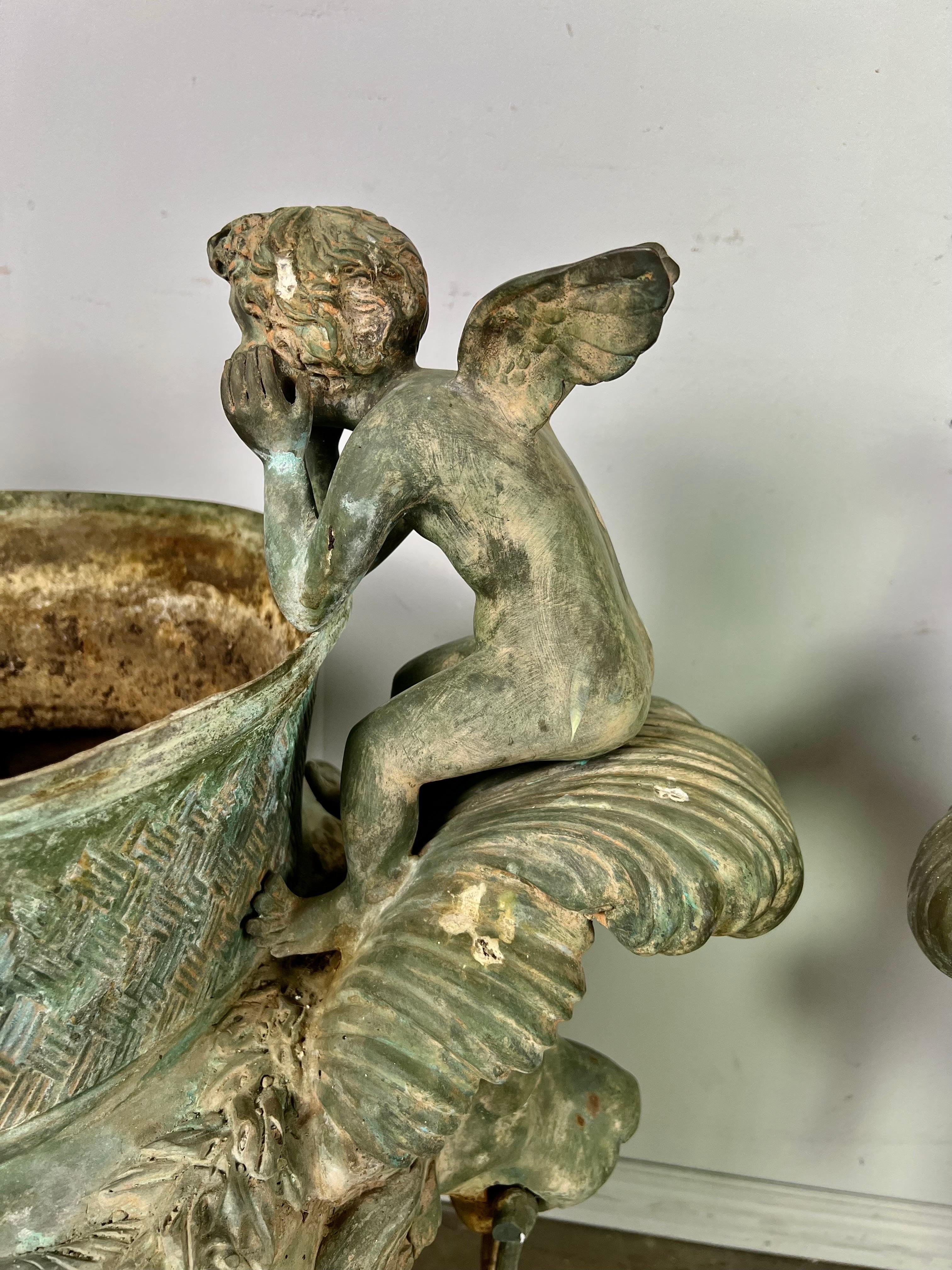 Monumental size pair of French Bronze Planters with Cherubs. They are detailed with garlands of flowers, acanthus leaves, and two exquisite cherubs gazing at each other. The patina on these planters is unbelievable. They have the most beautiful