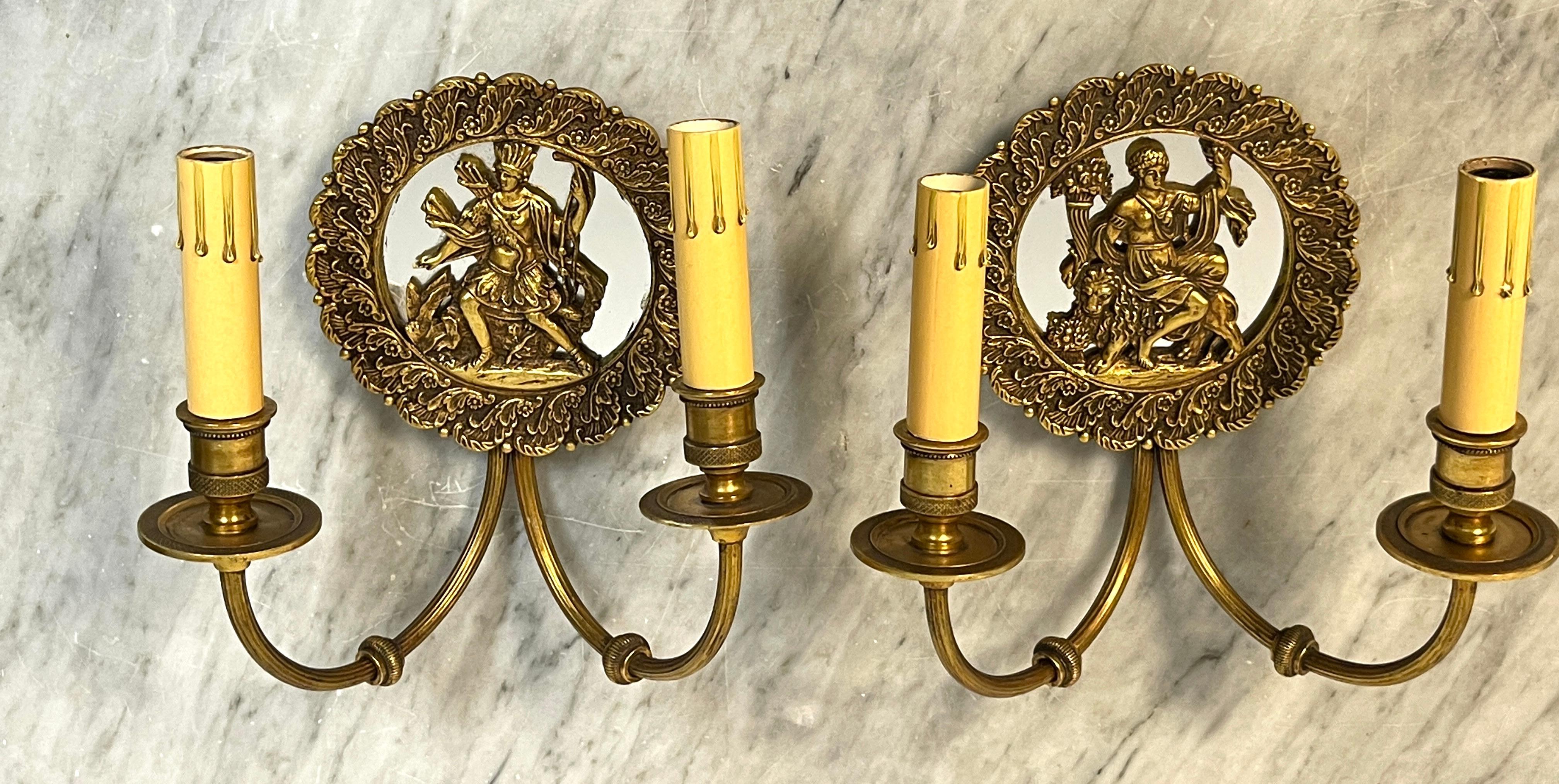 Pair of French Bronze & Mirror Medallion 'America & Europe'  Wall Sconces  
France, circa 1950s

A fine pair of of French bronze wall sconces one each one with a  5.5 Inch diameter mirrored backed vignettes, one depicting the Americas with an