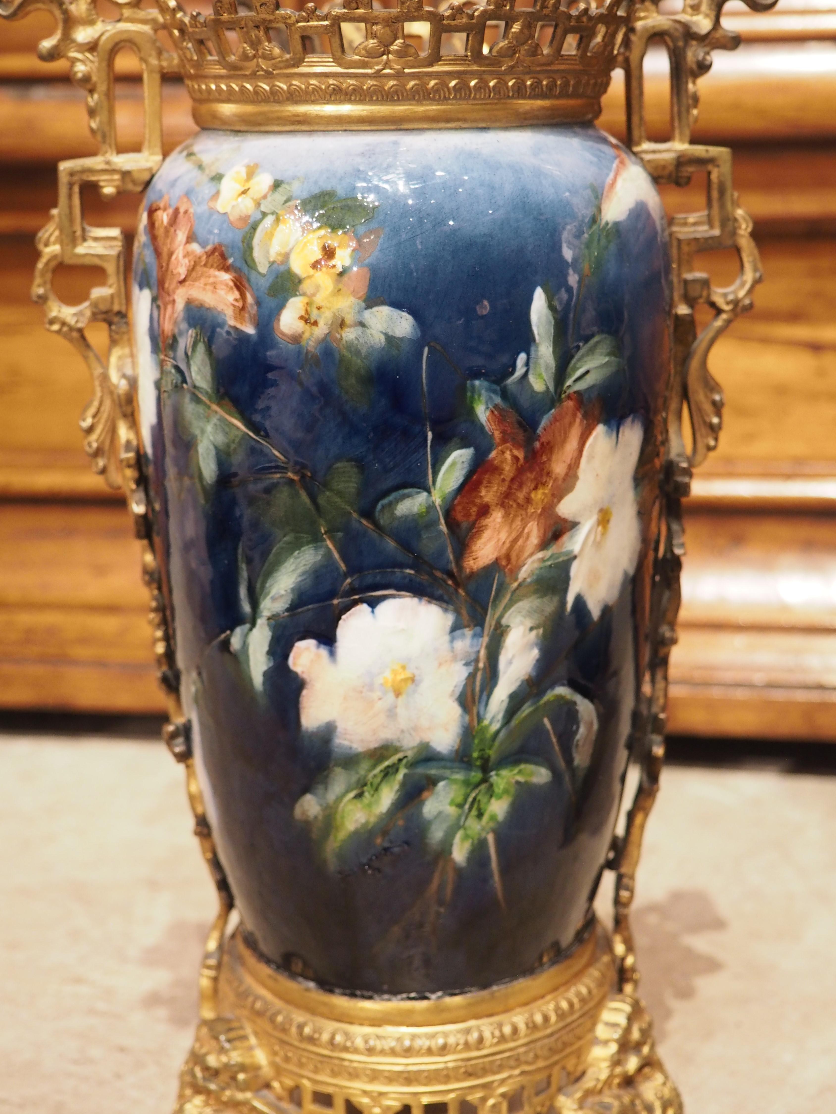 Peinte à la main dans la commune française de Montigny-sur-Loing, vers 1860, cette belle paire de vases barbotine montés en bronze est signée sur la face inférieure. La barbotine est une bouillie céramique (mélange d'argile et d'eau) utilisée en
