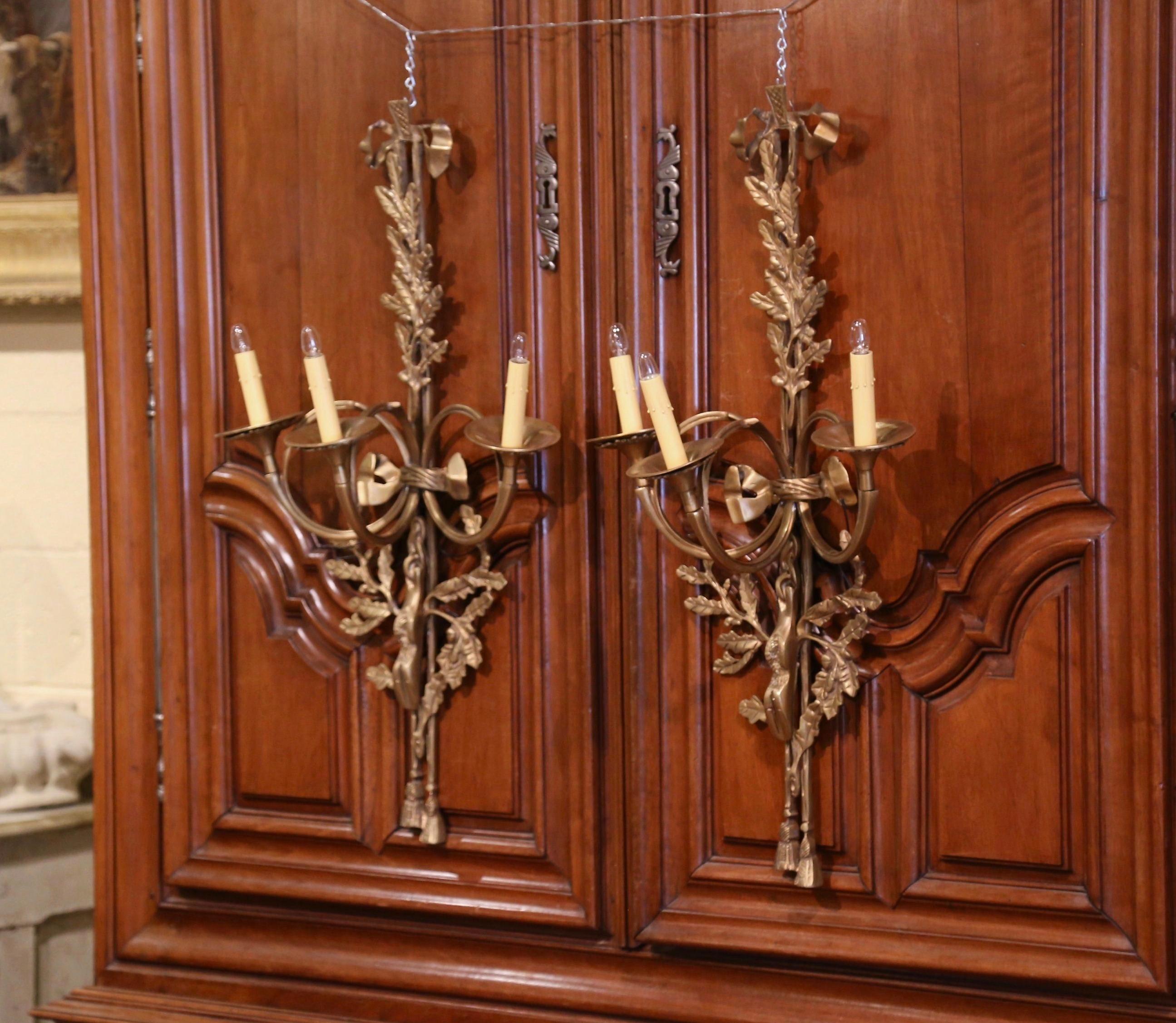 Decorate a hunting lodge or ranch house with this elegant pair of tall vintage sconces. Created in France circa 2010 and made of bronze, each wall light has three horn shaped arms newly wired and dressed with decorative candle sleeve covers. The