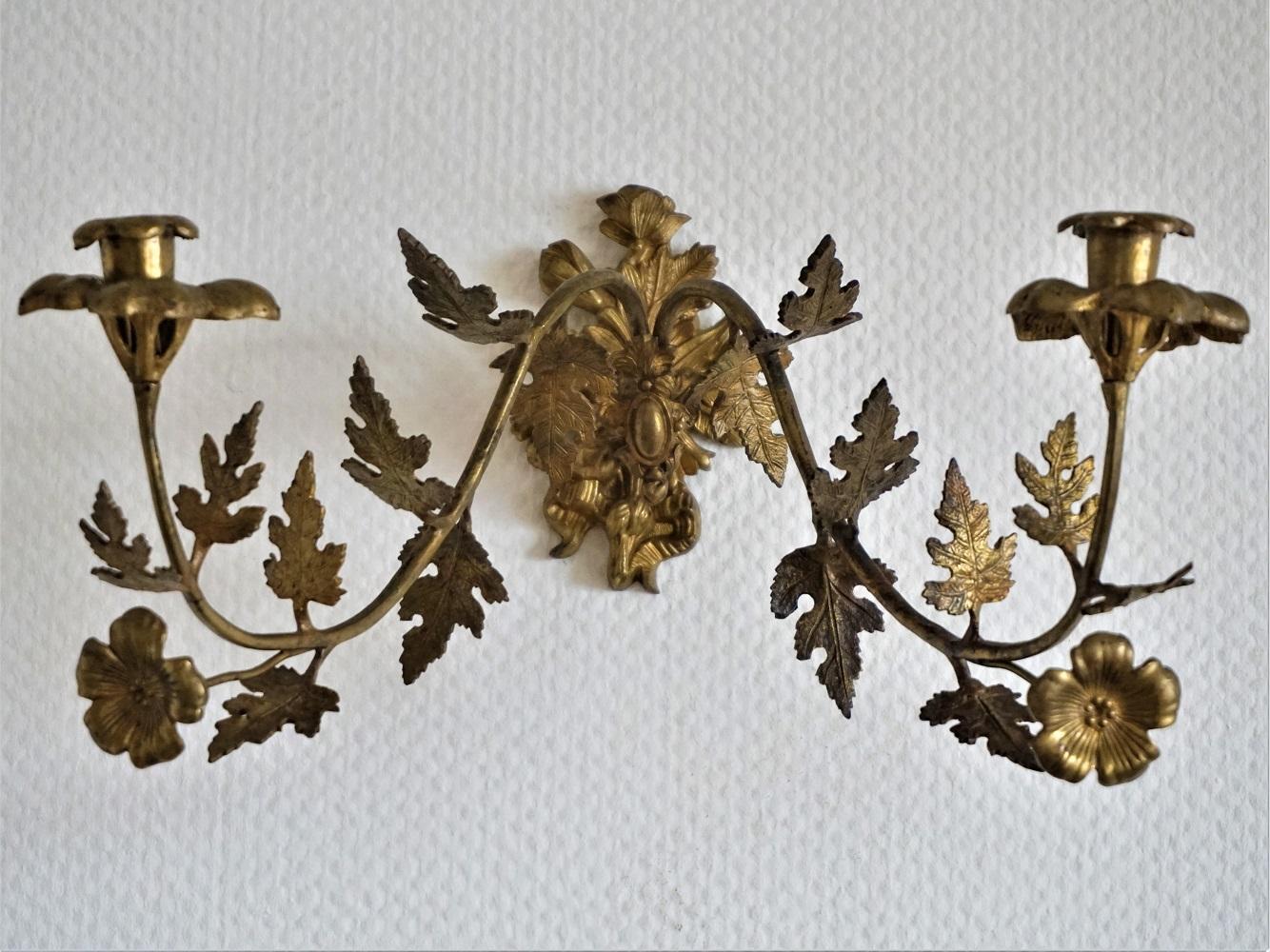 A pair of french two-arm wall candle sconces, gilt bronze and brass decorated with leaf and floral motifs, beautiful aged patina.