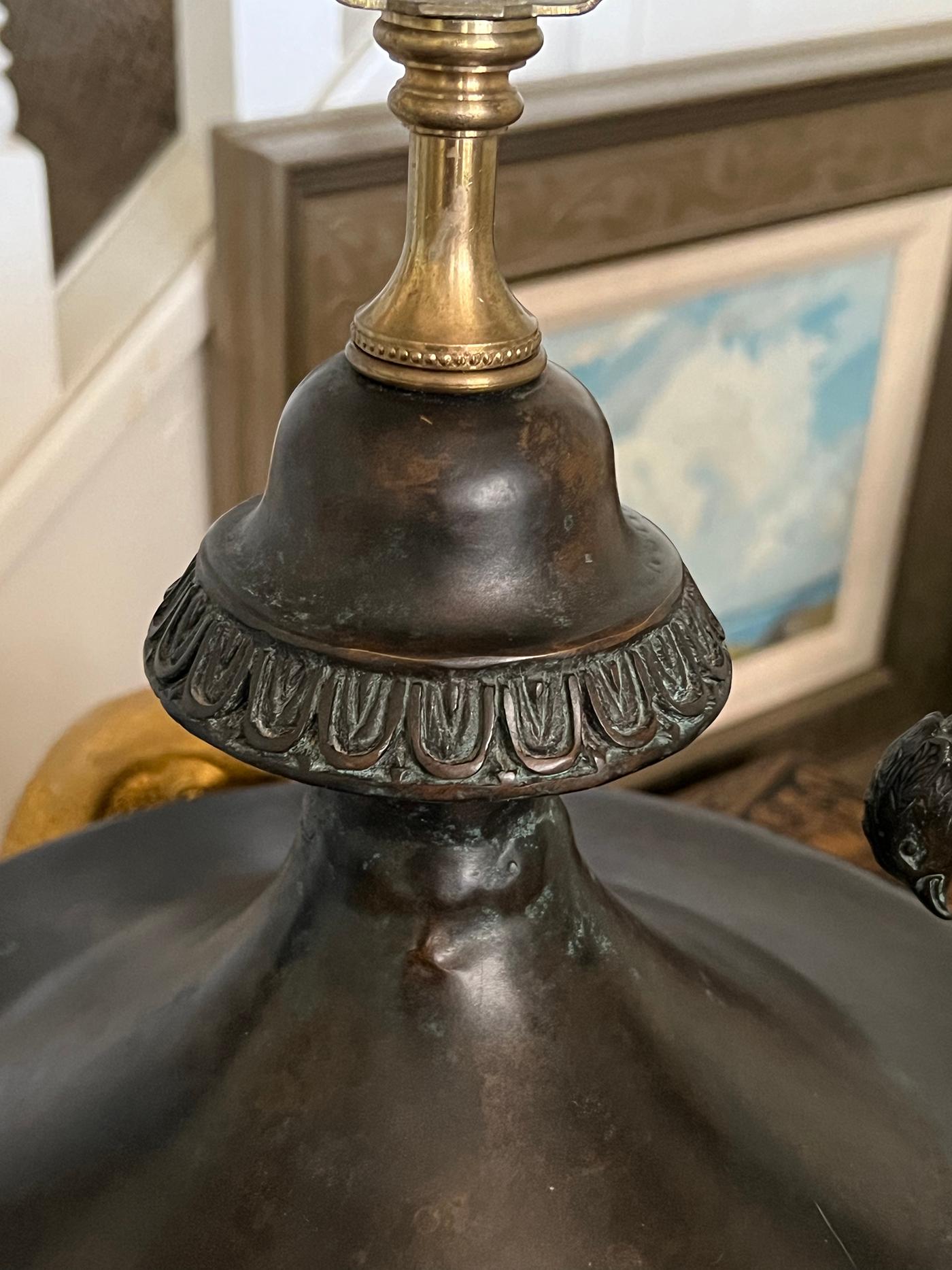 each boldly-scaled lamp with flared top above a cup-shaped body adorned with a guilloche perimeter band and bell-flower swags surrounding half-profile portraits; resting on a splayed circular base over a black marble plinth