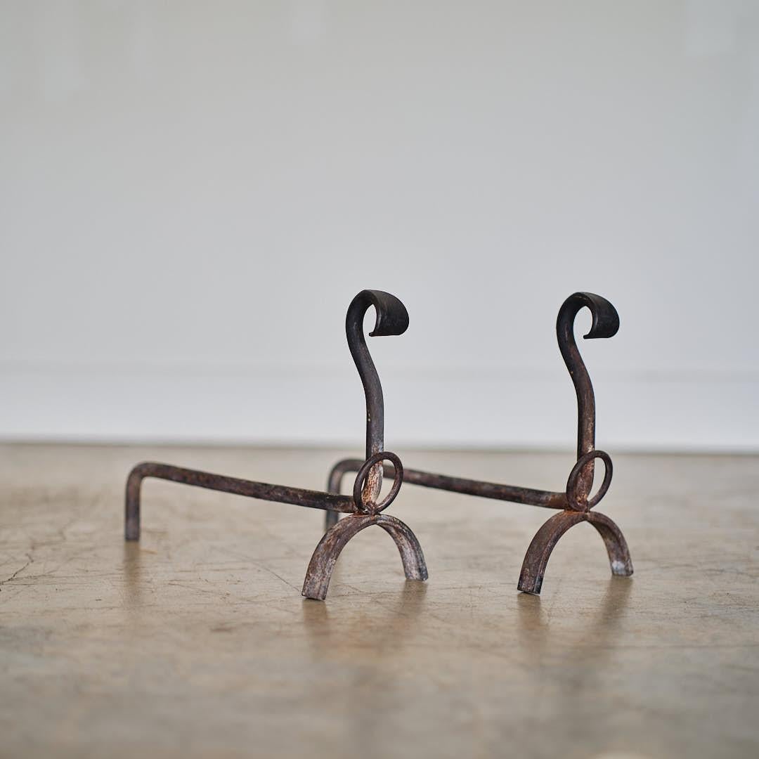 Unique pair of Brutalist andirons from France, 1950's. Heavy forged iron with arched base and ring detail. Surface shows great age, rust and patina. 