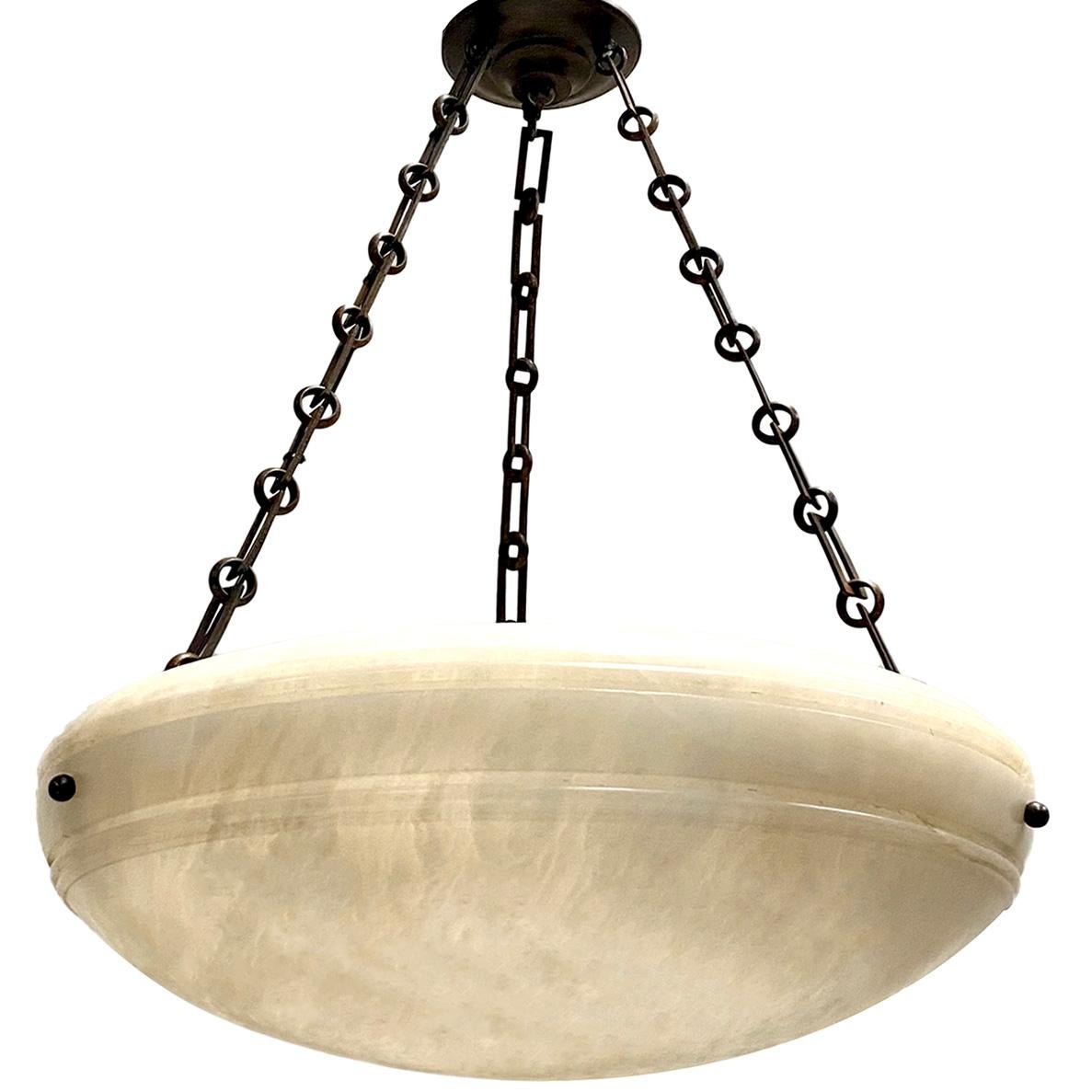 Coppia di lampade francesi in alabastro scolpito degli anni '50 circa con 3 luci interne Edison e catena e baldacchino in bronzo patinato. 
Venduto singolarmente.

Misure:
Diametro: 23