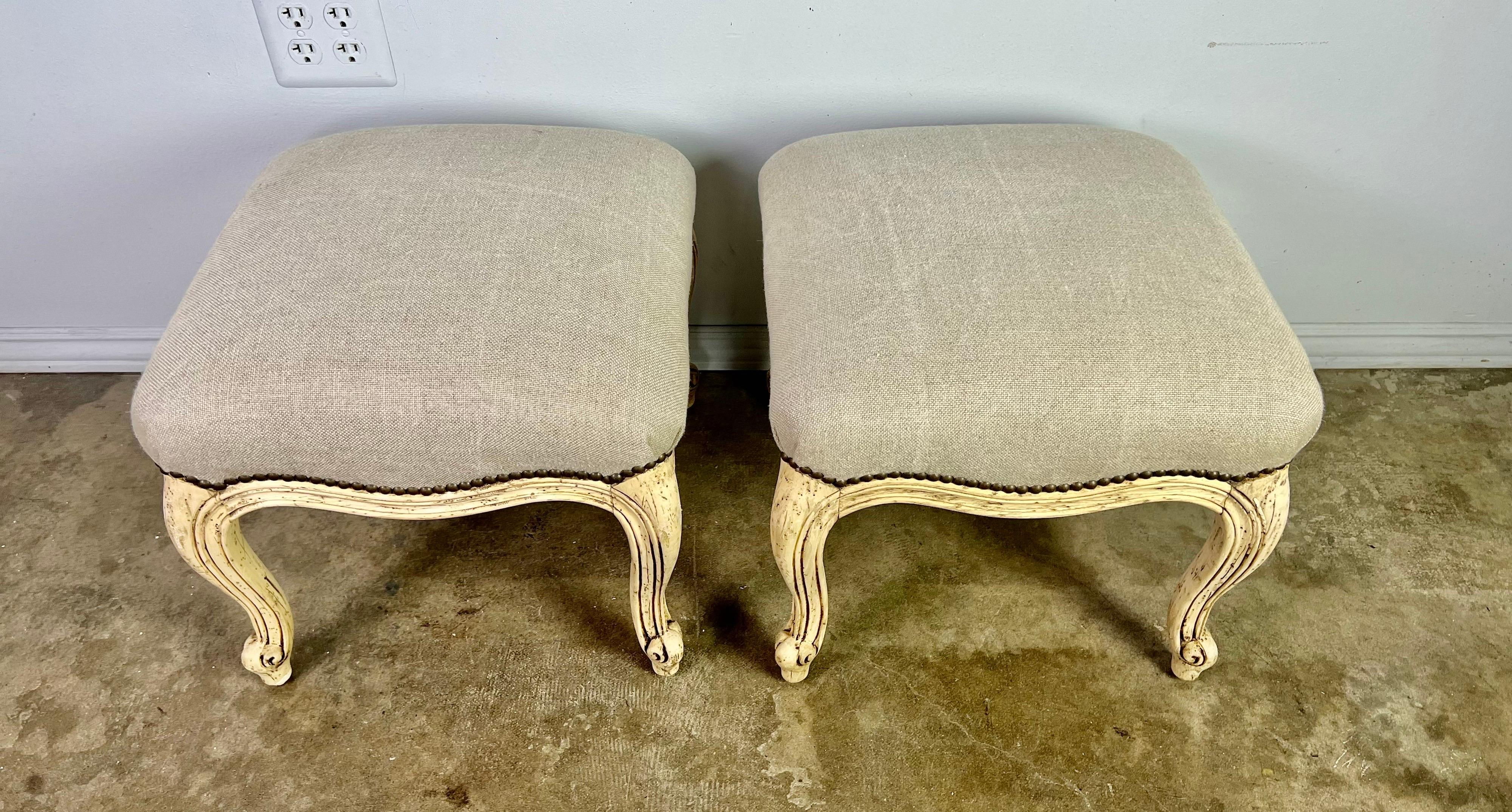 Pair of French painted Louis XV style benches standing on four cabriole legs with rams head feet. The benches are newly upholstered in a washed Belgium linen with nailhead trim detail.