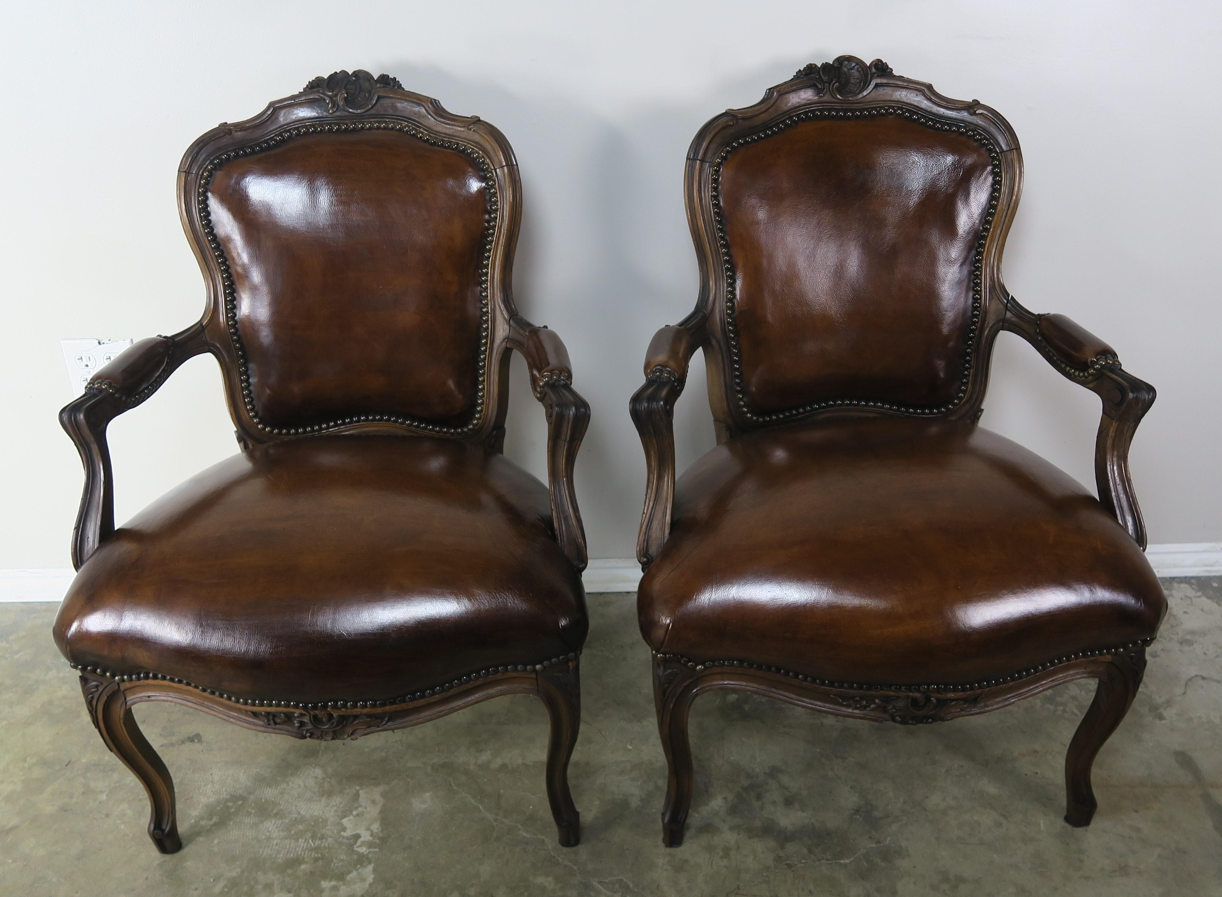 Pair of French carved armchairs standing on four cabriole legs. The chairs are upholstered in rich tabacco colored leather and finished with antique brass colored nailhead trim detail.
Seat height 19
