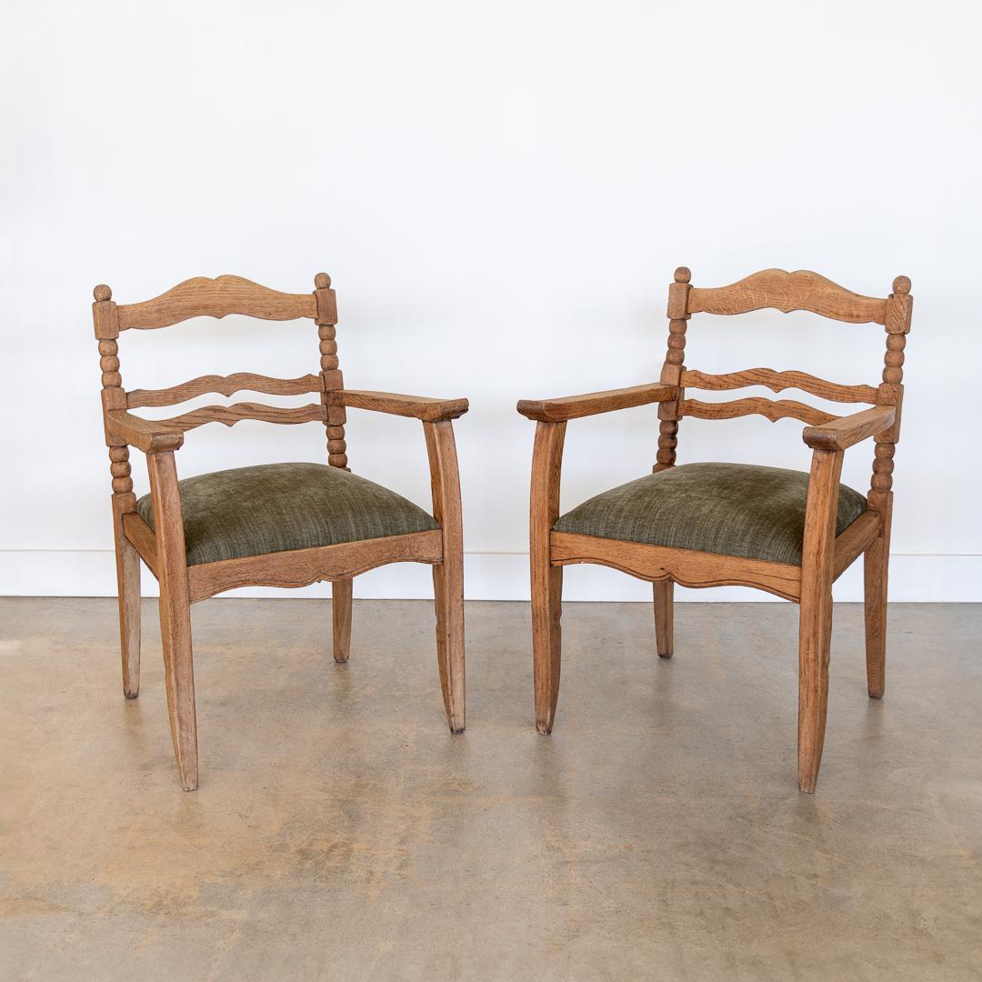 Wonderful pair of carved oak armchairs from France, 1940s. Beautiful ornate carved wood frame with bobbin and scallop detail. Newly upholstered seats in a textured green fabric. Original finish shows great age and patina. Chair has removable seat.
