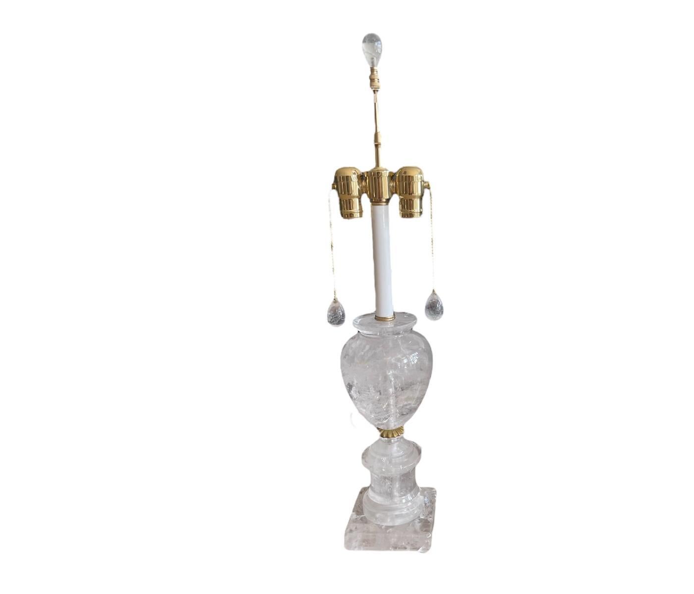 Un llamativo par de lámparas de sobremesa francesas de cristal de roca, del siglo XX. Cada lámpara presenta un cuerpo ovoide de cristal de roca finamente tallado y pulido a mano, que descansa sobre una roseta decorativa y una base escalonada,