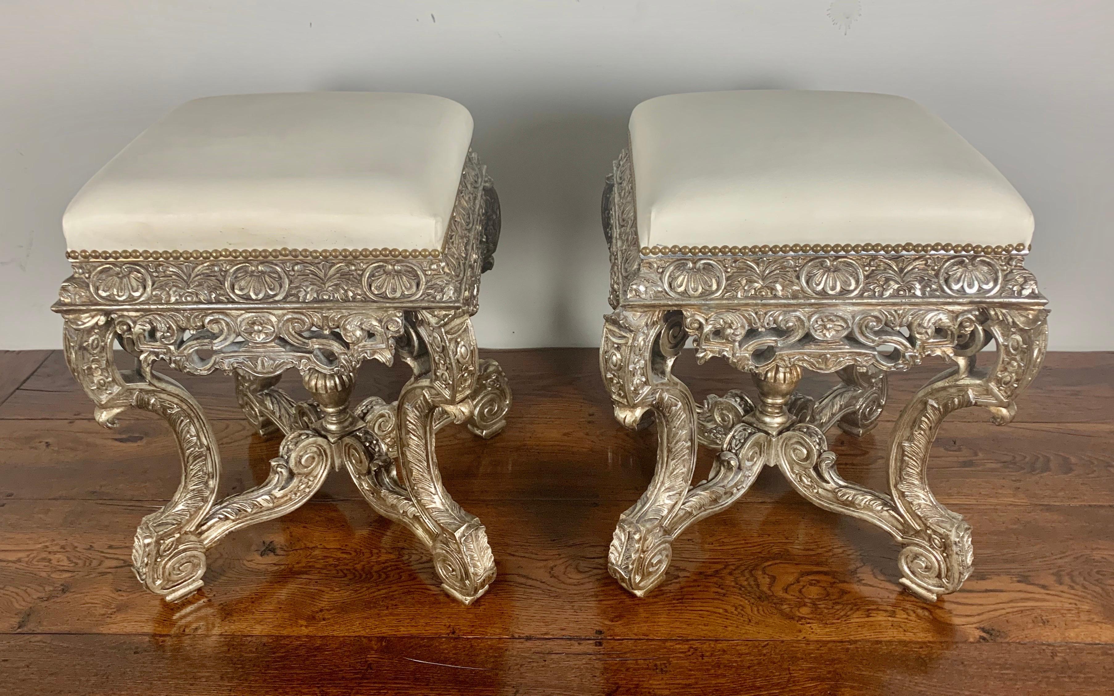 Pair of French carved silver gilt benches with white leather upholstery and nailhead trim detail.