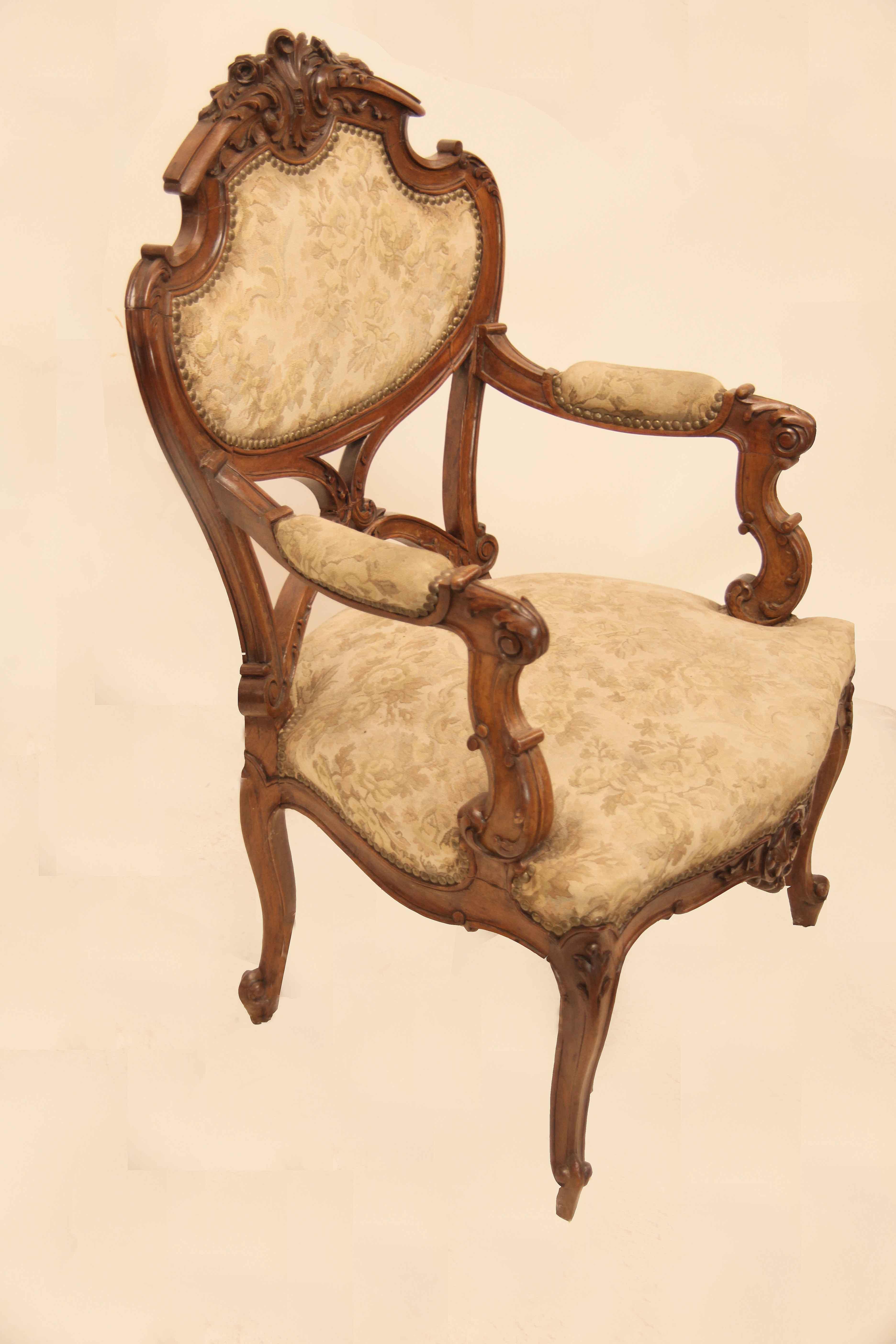 Pair of French carved walnut armchairs, this pair are heavily carved all over in high relief, the photographs show the various architectural and floral features (rosettes, acanthus, volutes,etc.). The serpentine shaped apron has a central carved