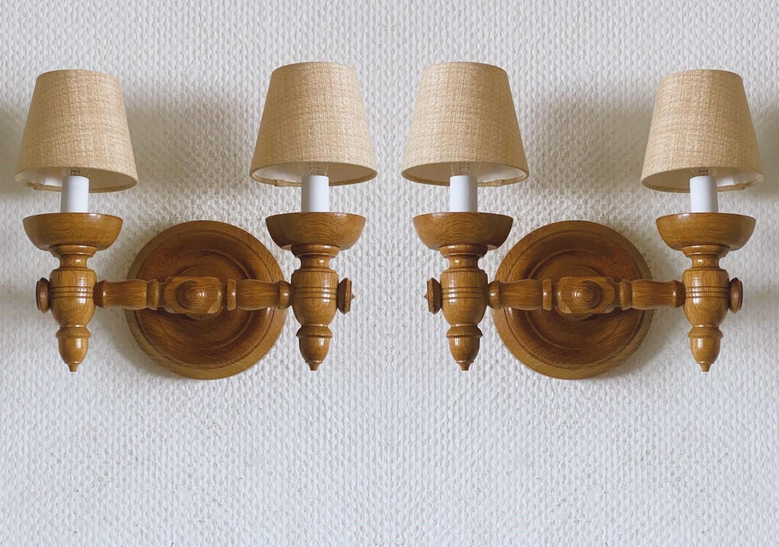 Une rare paire d'appliques murales à deux bras en chêne sculpté dans le style de  Charles Dudouyt, France, années 1940. Magnifiques détails sculptés à la main avec les abat-jours en tissu d'origine. Chaque applique peut recevoir deux ampoules E-14 à