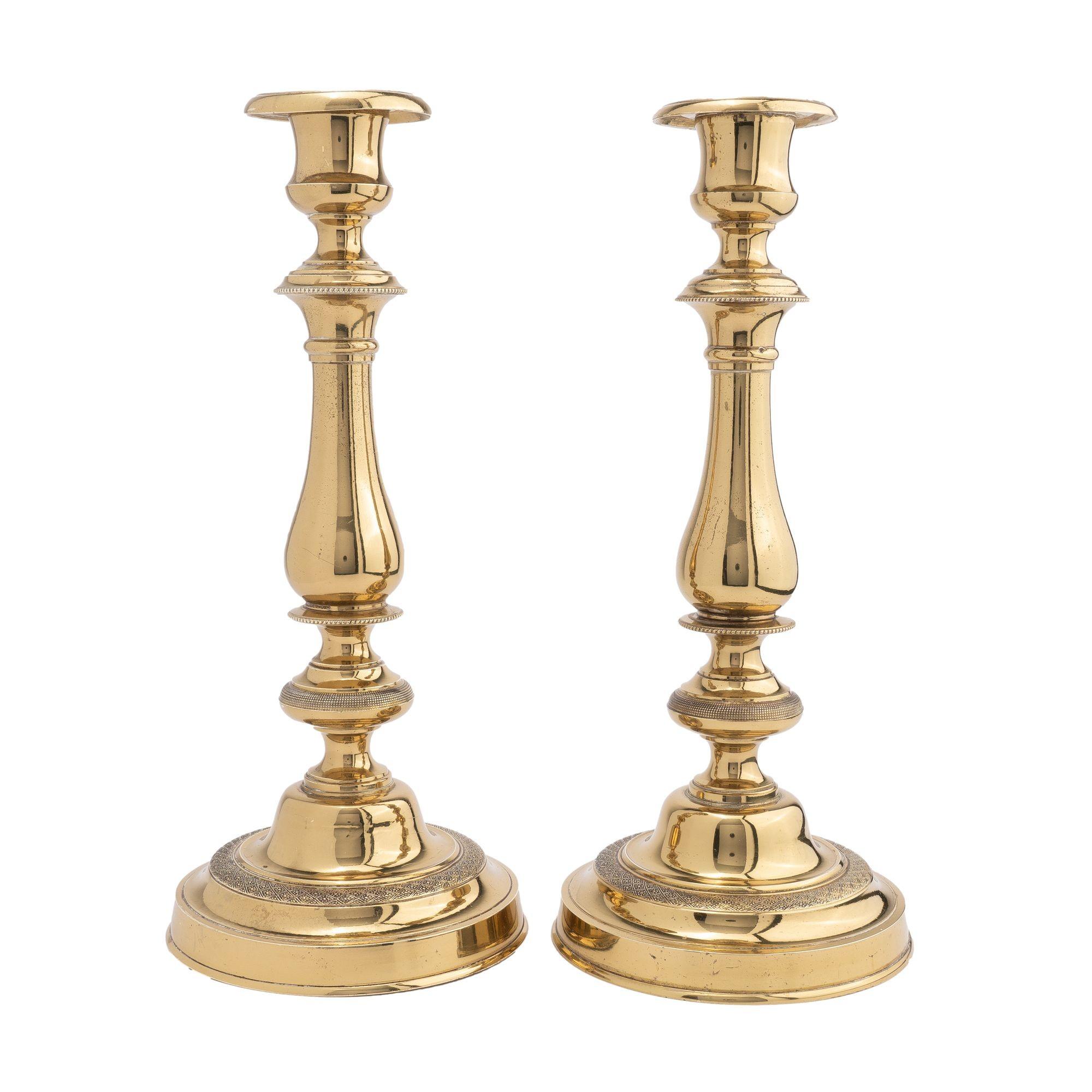 Pair of cast brass, engine turned, French Empire period candlesticks. The pear shaped candle shaft are framed by beaded reel turnings and an engine turned knob above a raised engine turned circular base. The shaft supports an urn form candle cup