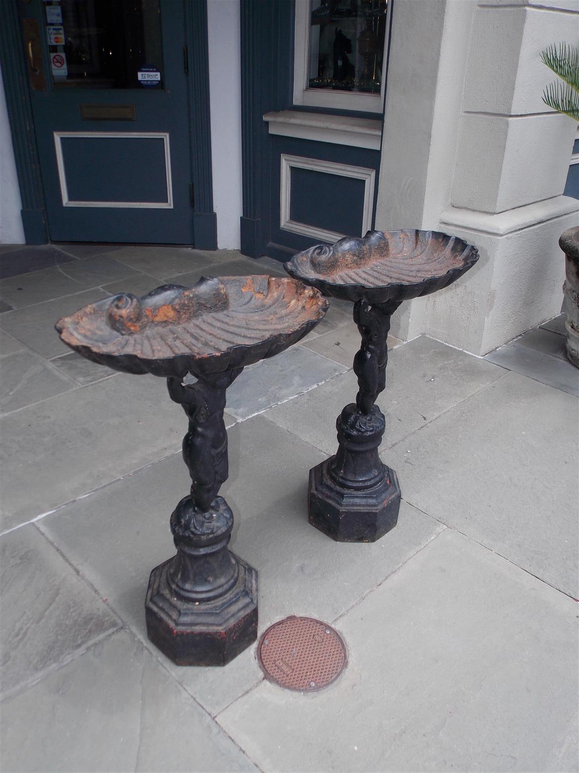 Pair of French cast iron painted figural cherub bird baths with flanking shell form bowls, and resting on a circular ringed octagonal plinths. Mid-19th century

Pair of bird baths are 32.25 Tall / 21 Wide at top / 13.25 Deep at top / 11 Square at