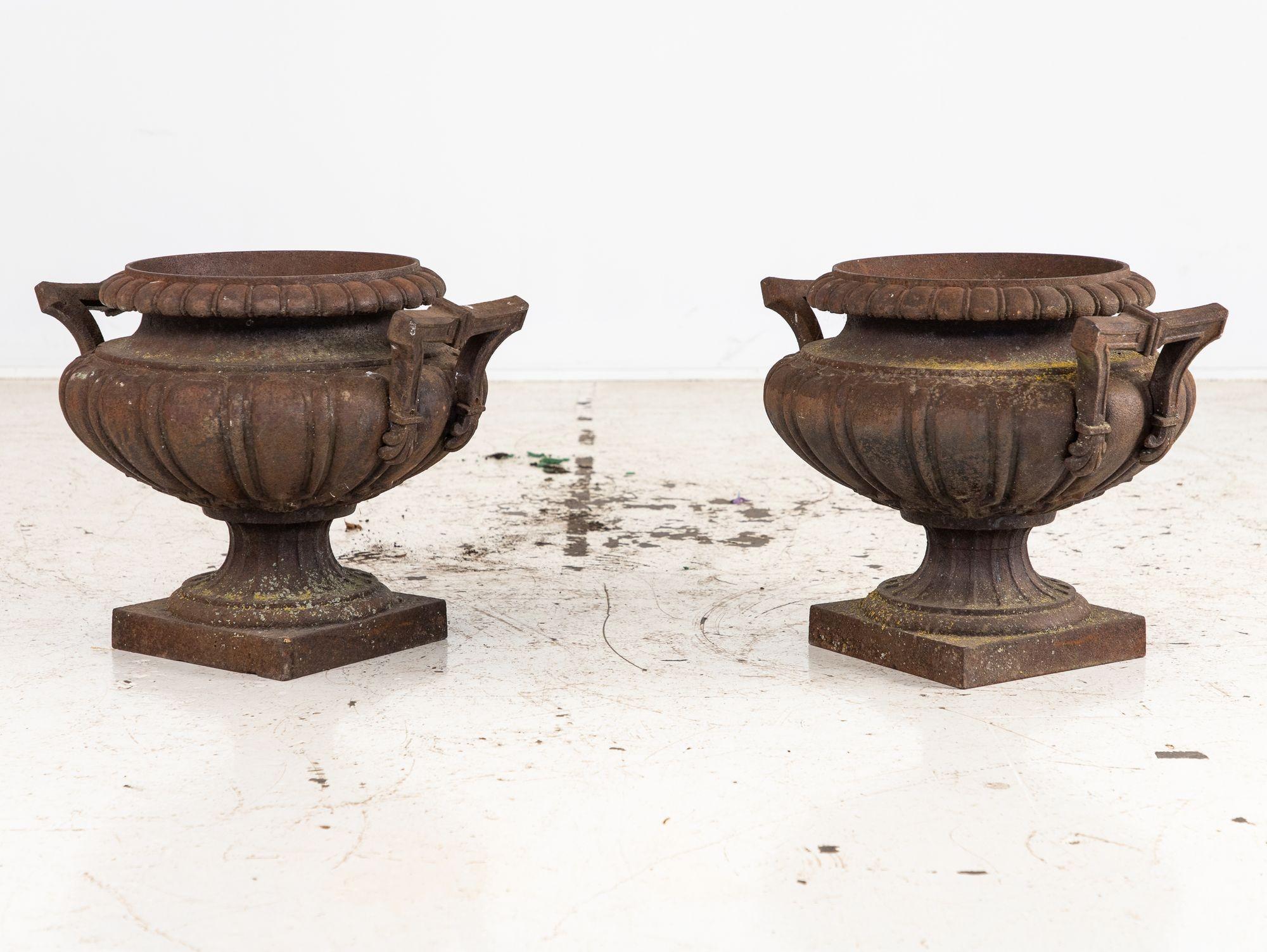 Questa coppia di urne da giardino in ghisa francese dell'inizio del XX secolo emana un'eleganza senza tempo e una ricca storia. La loro patina invecchiata e arrugginita mostra decenni di invecchiamento, aggiungendo autenticità al loro fascino. Il