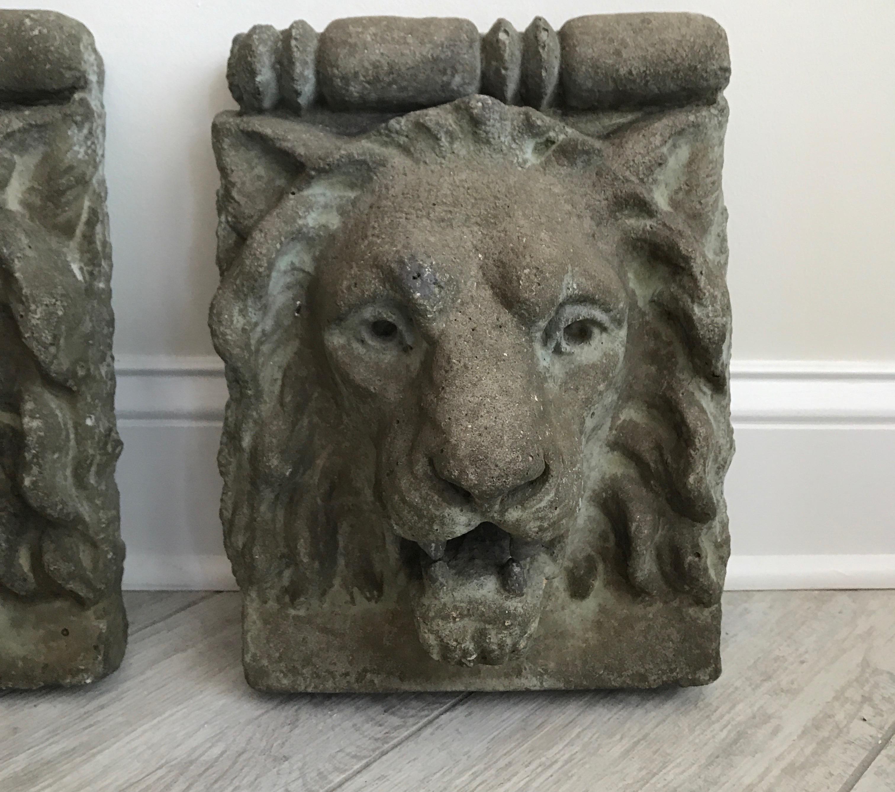 Pair of lion head cast stone wall hangings.
