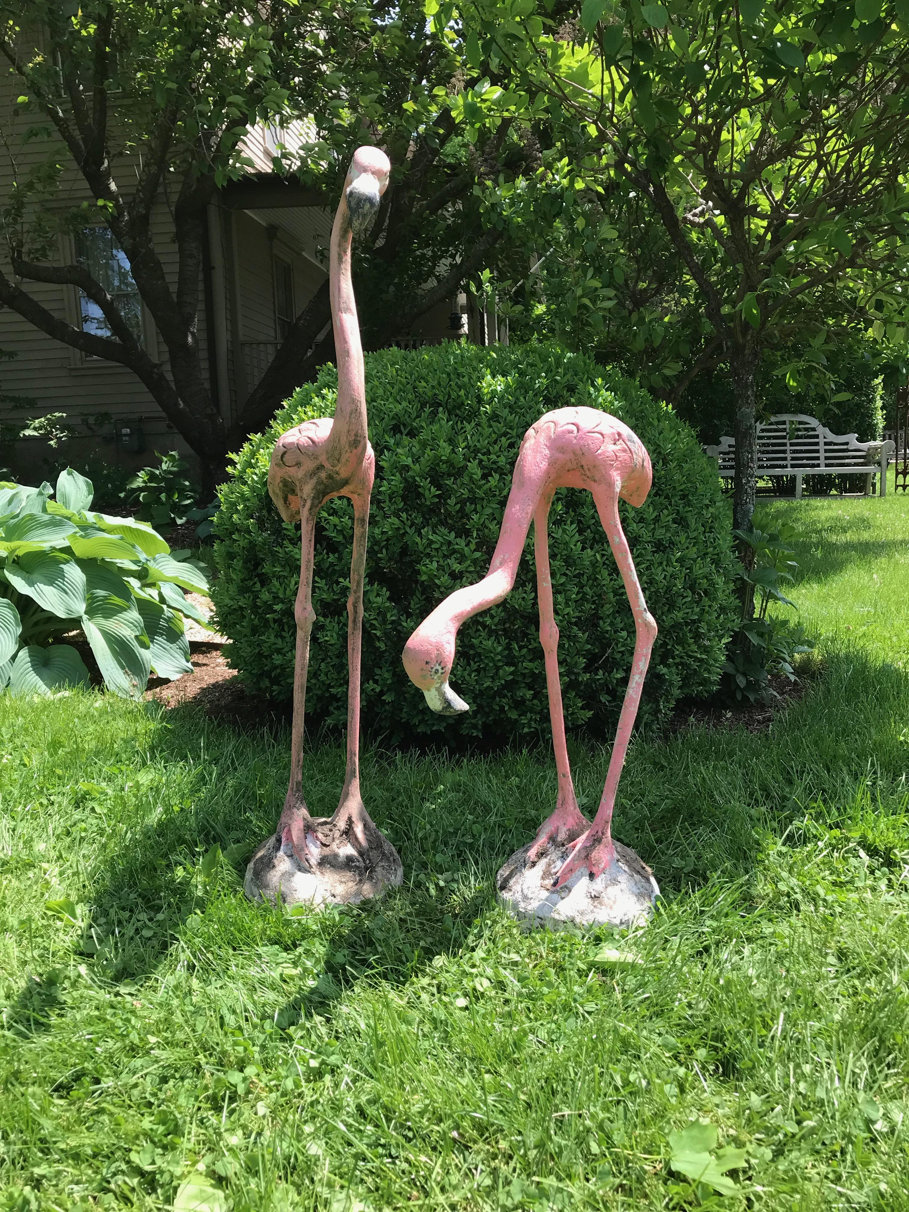 For all you fans of Classic garden flamingos, these are the real deal. Entirely made of cast stone over an iron armature, and with a weathered and old, likely original, pink and black painted surface, the form and detailing on these flamingos is