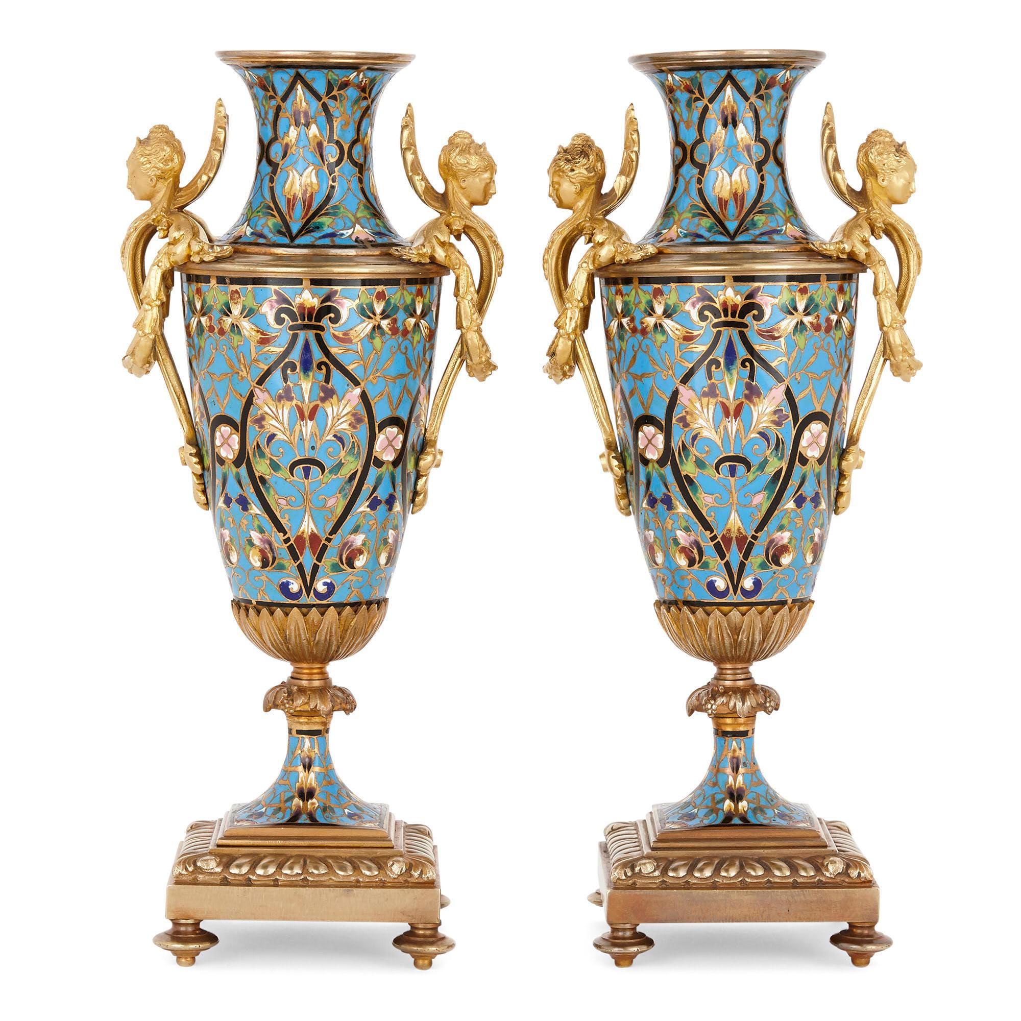 This magnificent pair of vases is wrought from gilt bronze and champlevé enamel in the distinctive, visually striking Renaissance Revival style. The cylindrical body of each vase is profusely adorned with champlevé enamel, the enamel fashioned into