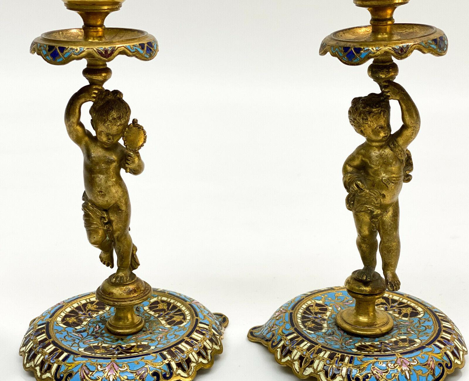 Pair of French Champleve Enamel Bronze Candlesticks, Late 19th Century

Blue and pink floral enamel t0 base and sconce. The stem depicts two putti with ribbons adorning their bodies.

Additional Information:
Material: Bronze, Enamel 
Model:
