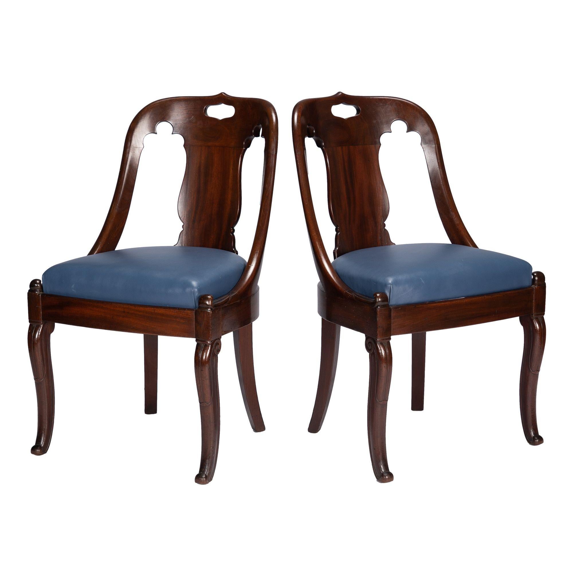 Pair of Charles X period, French Restoration, mahogany “chaise en gondole” chairs with leather upholstered boxed slip seats. The chair backs have a single vertical urn silhouette back splat below a crest rail pierced with a handle grip. The chair