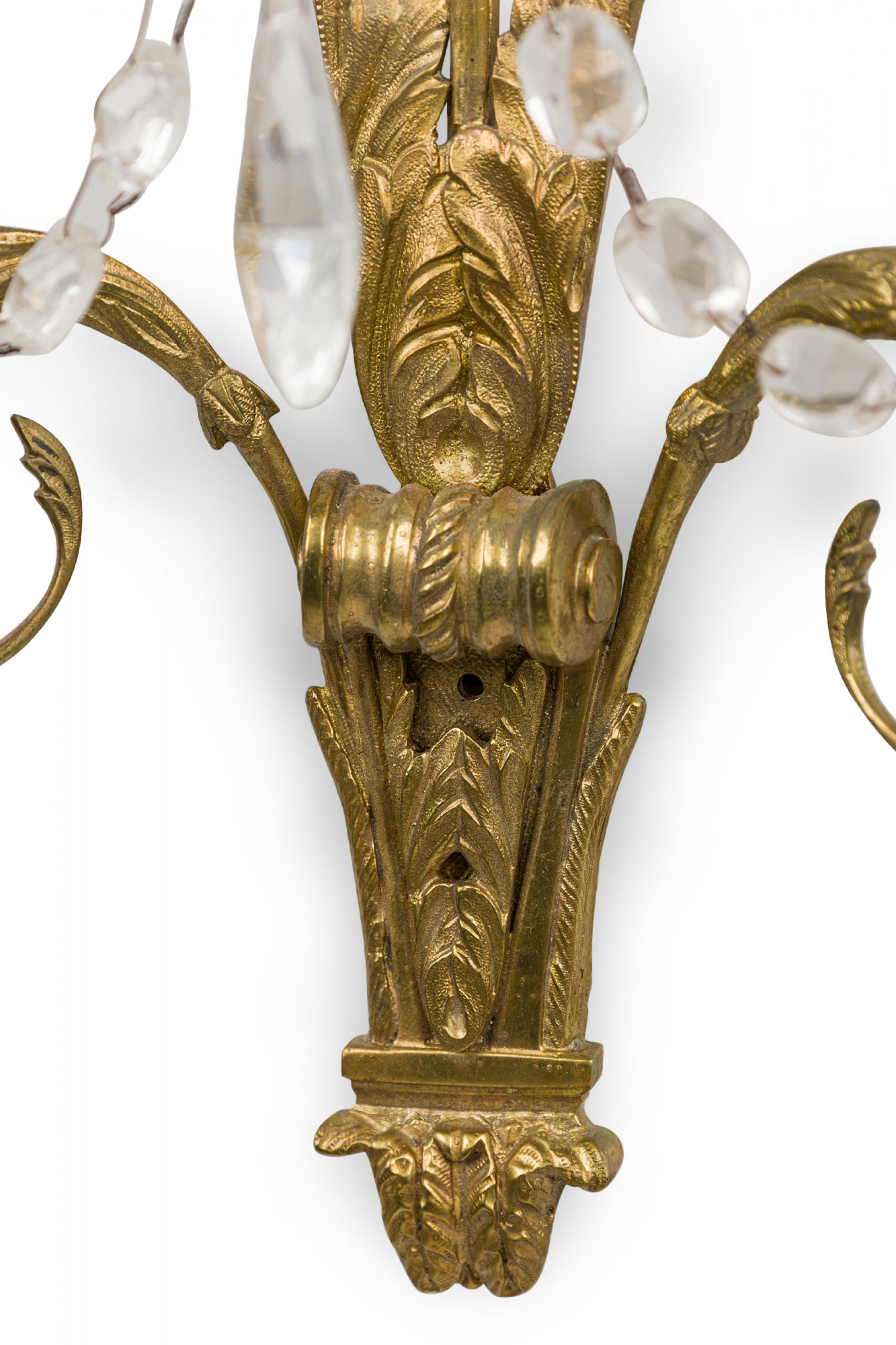PAR de apliques franceses de bronce dorado estilo Charles X (s. XIX/XX) con dos brazos portavelas, un cristal piramidal central y cristales facetados en forma de lágrima colgando por todas partes. (PRECIO POR PAR)

Estado: Bueno; Desgaste acorde con