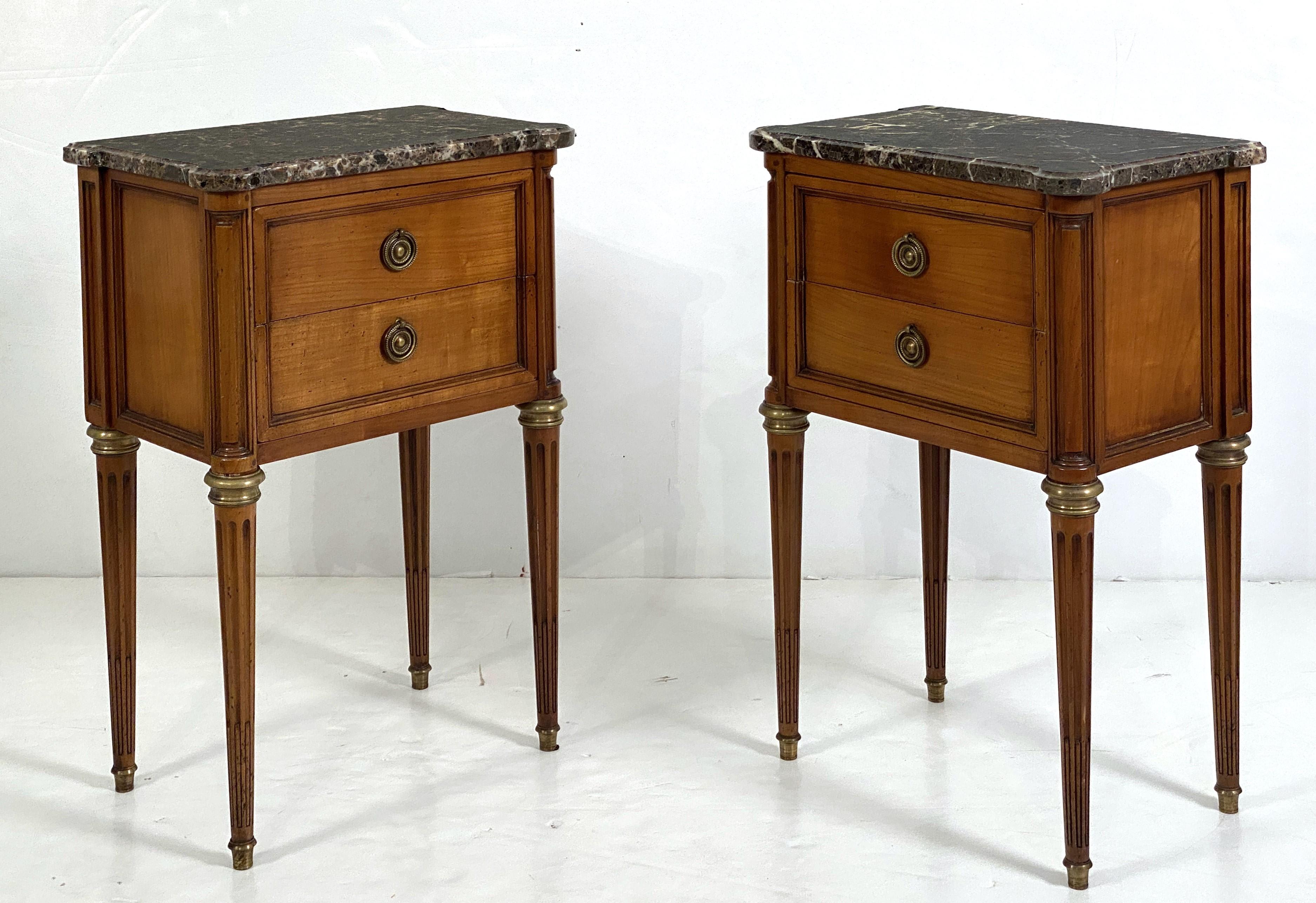 A fine pair of French bedside end tables or night stands - each stand featuring a figured marble-top 
over a frieze with two inlaid drawers with original brass pulls. 
Superb original figured marble tops flecked with varying shades of brown, grey