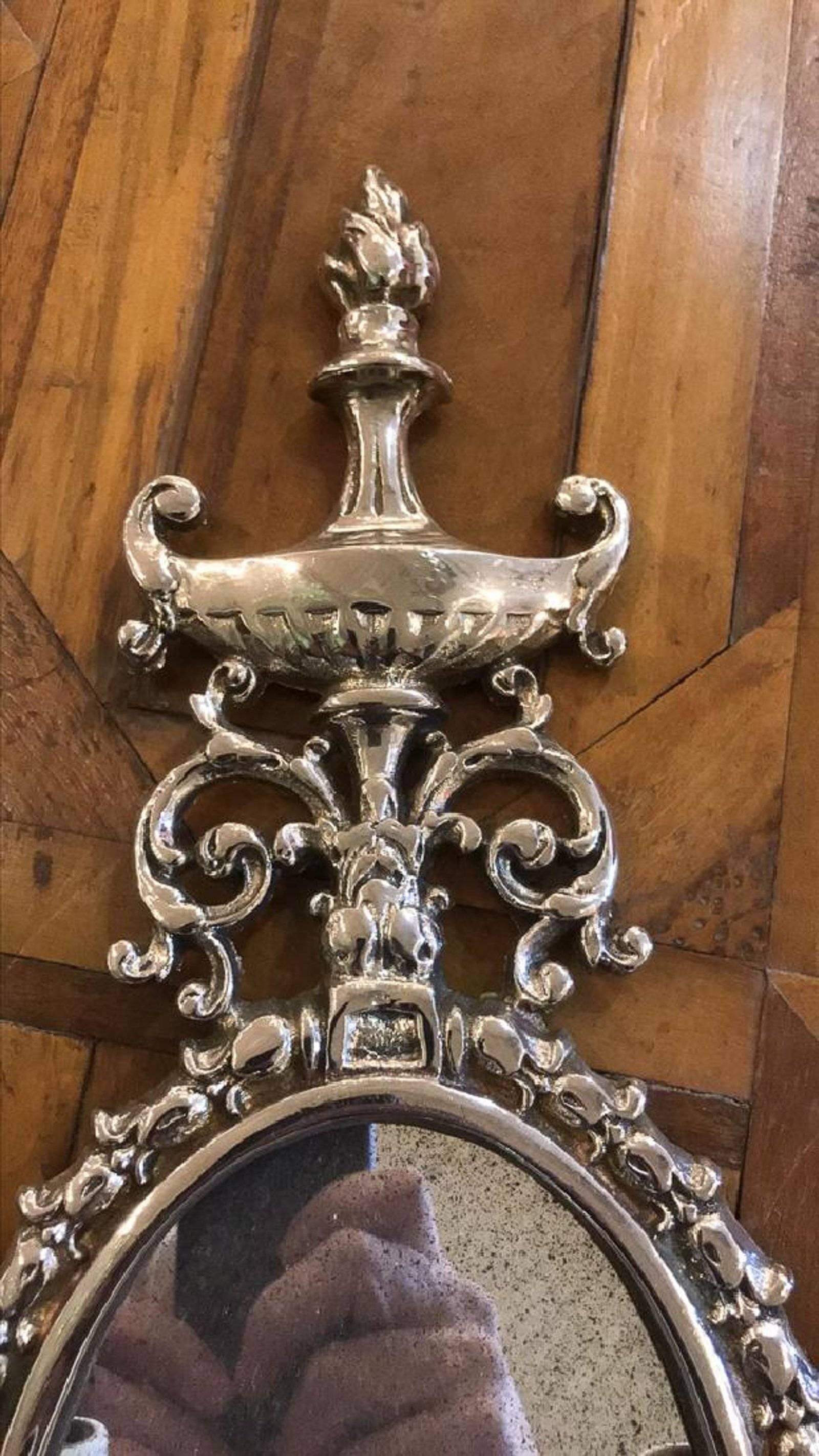 Uniquely styled French Classical chromium-plated two light wall sconces with urn, leaf scroll, tassel, and flame finial motif. Old mirror glass, recently electrified with new wax sleeves.