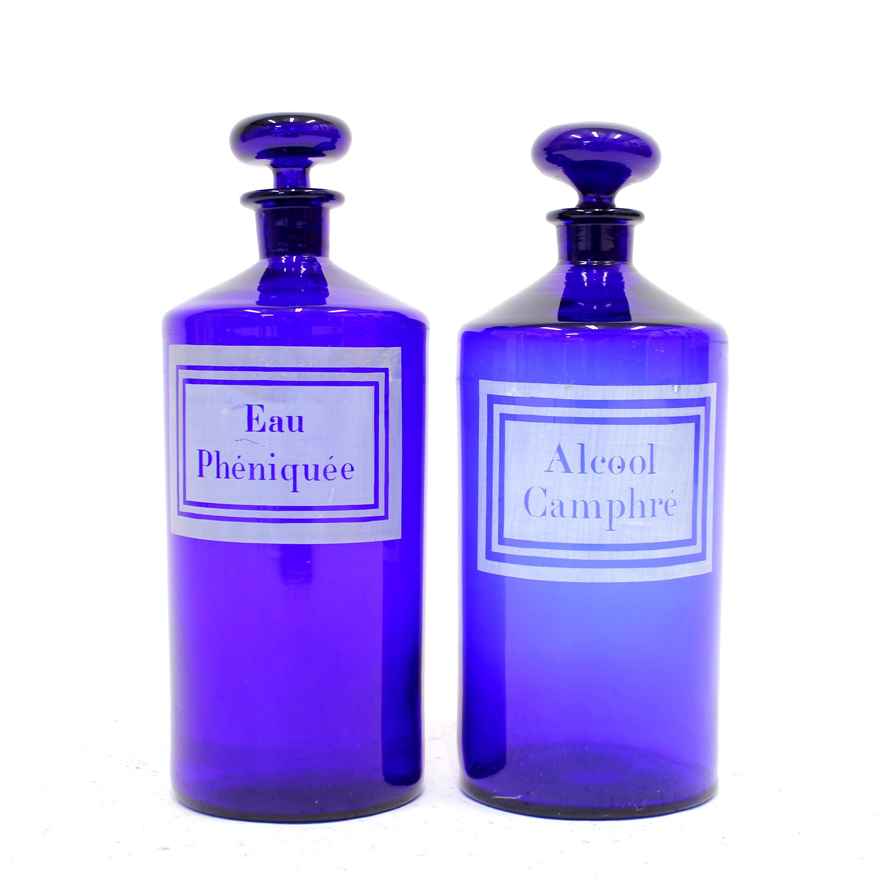 Pair of French cobalt blue apothecary, pharmaceutical or medicin bottles with lids from early 20th century. Frontside with white printed / painted frame with text of content. One marked 