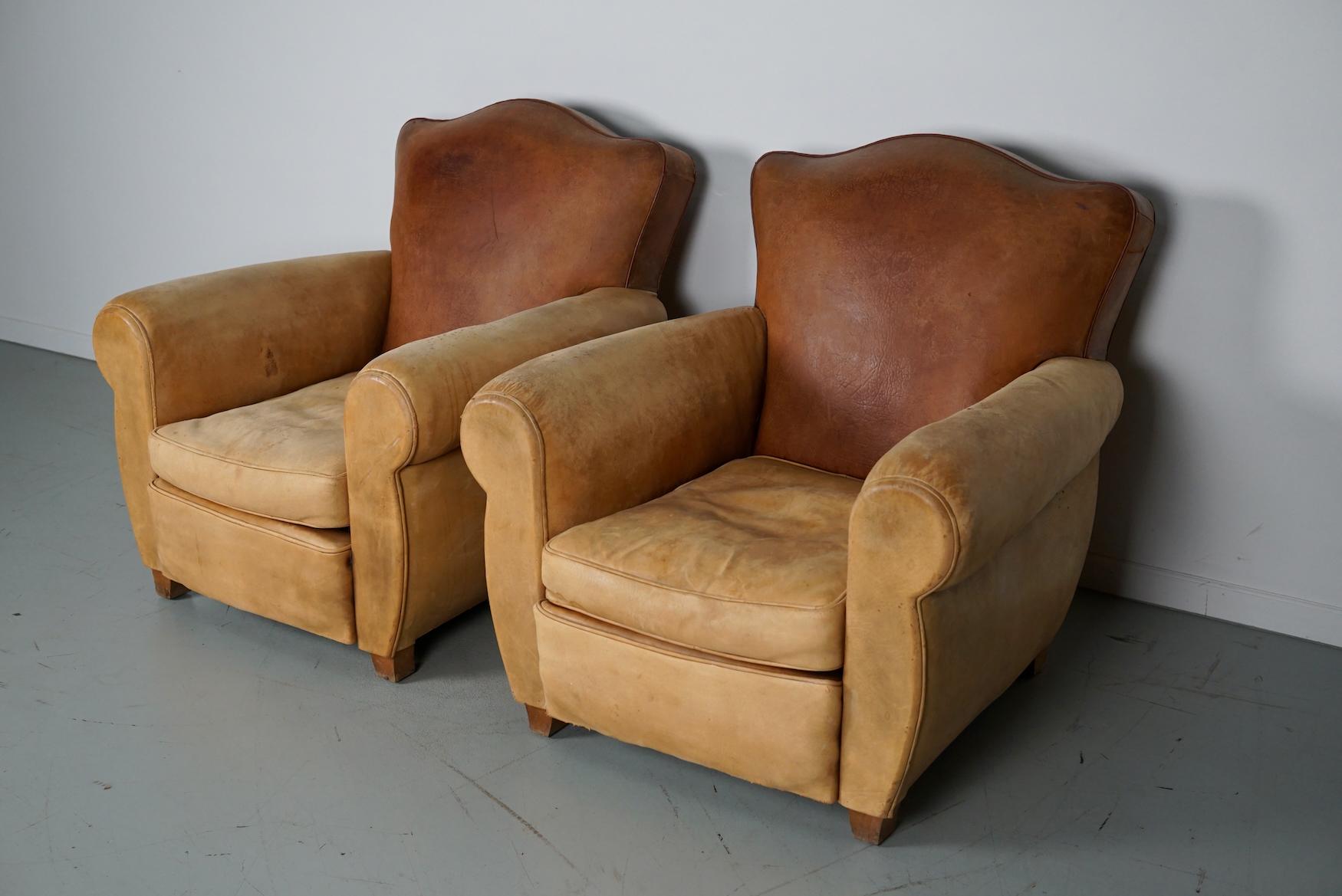 Ces fauteuils club ont été conçus et produits en France dans les années 1940. Les chaises sont fabriquées en cuir cognac maintenu par des broches métalliques et montées sur des pieds en bois.