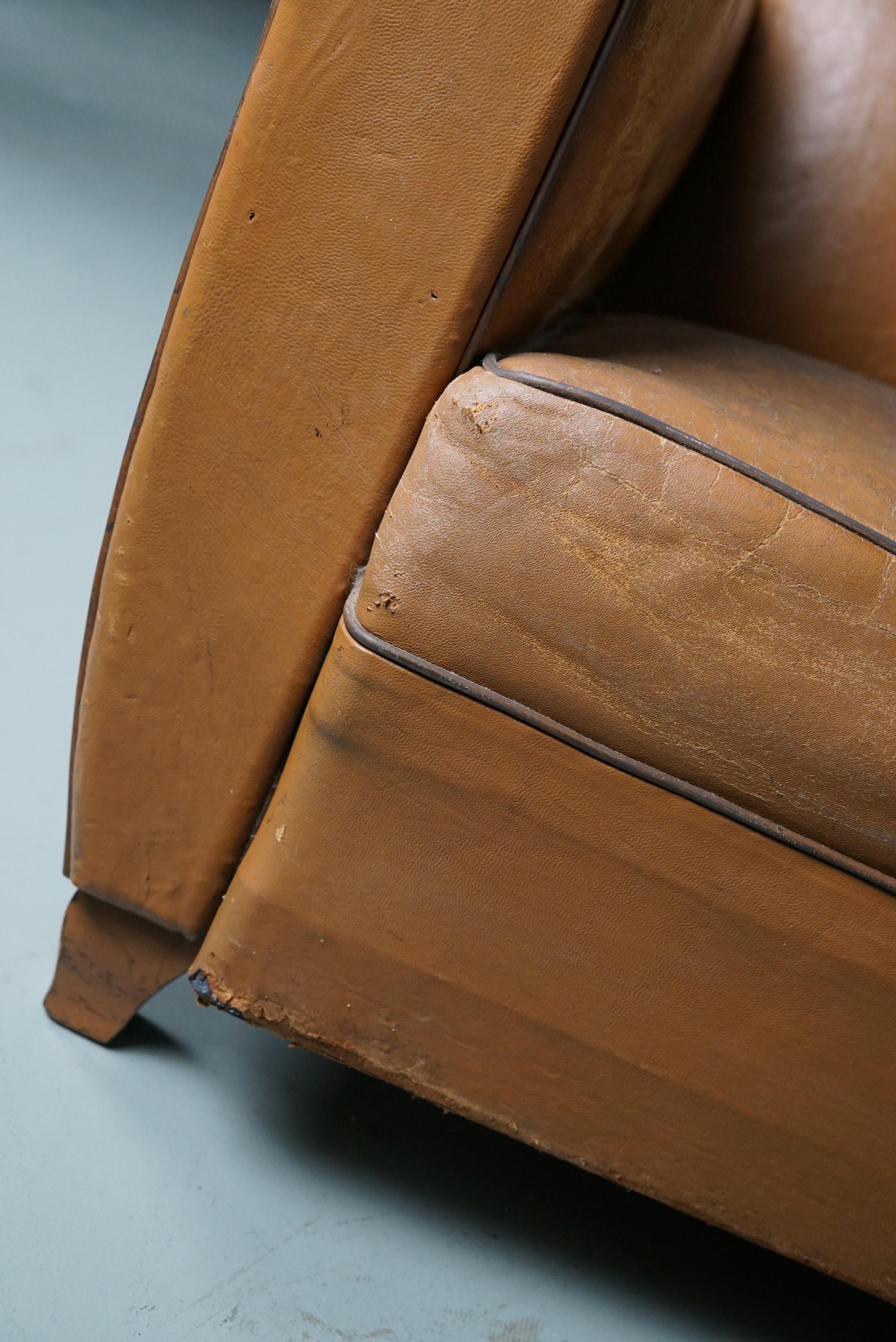 These club chairs were designed and produced in France during the 1950s. The chairs are made from cognac leather held together with metal pins and mounted on wooden legs.